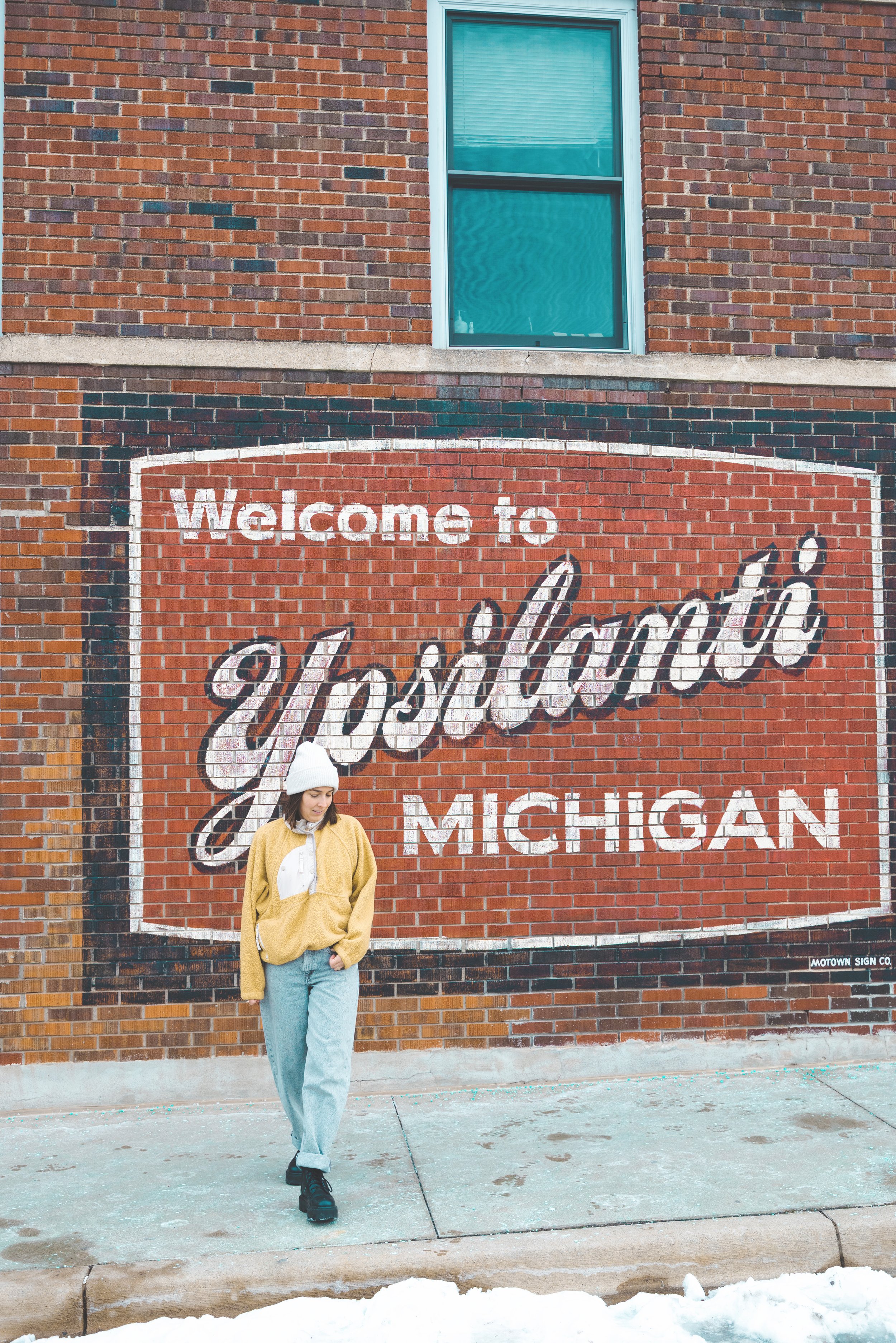 girl standing in front of welcome to ypsilanti mural