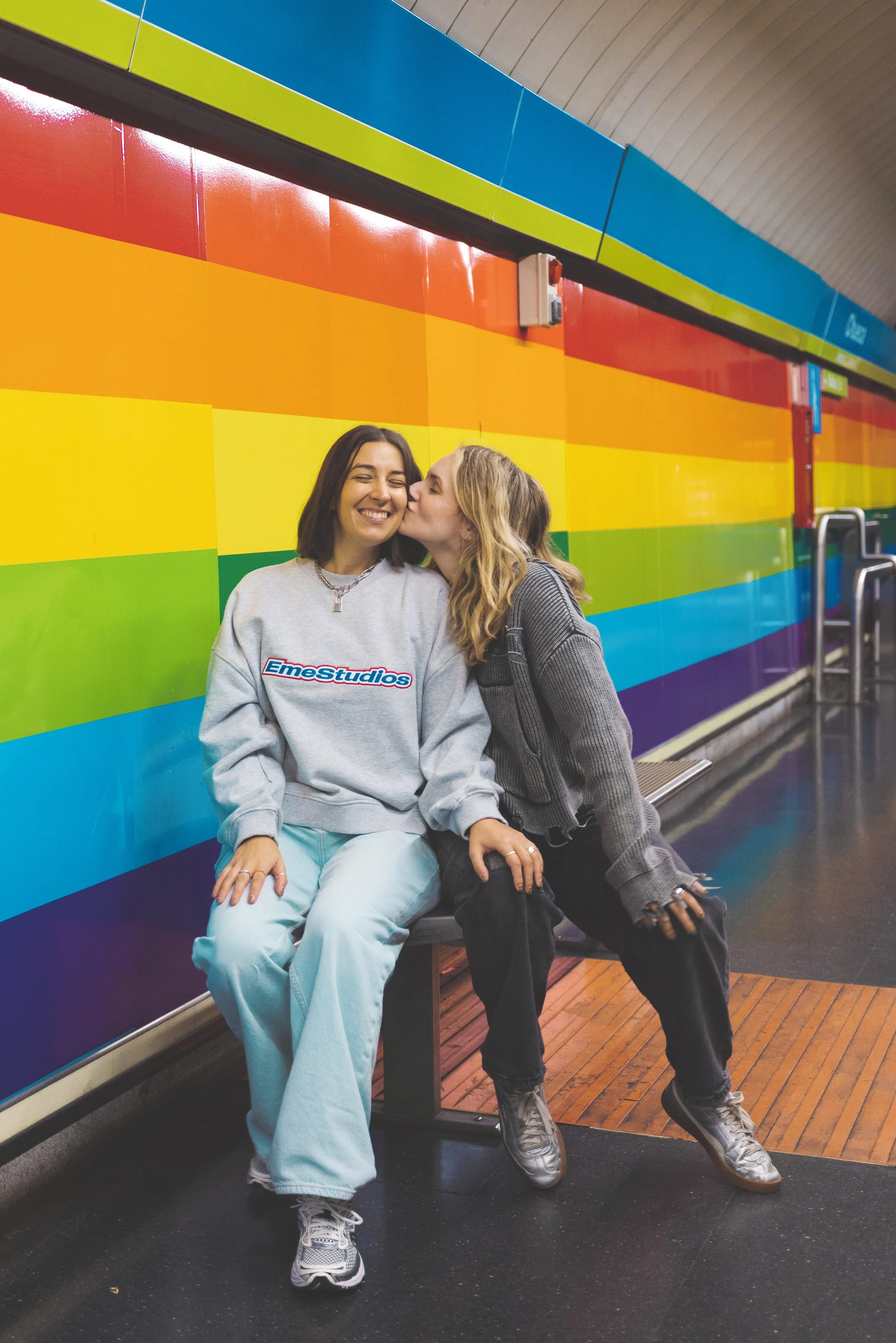 two girls kissing in chueca's rainbow metro station madrid