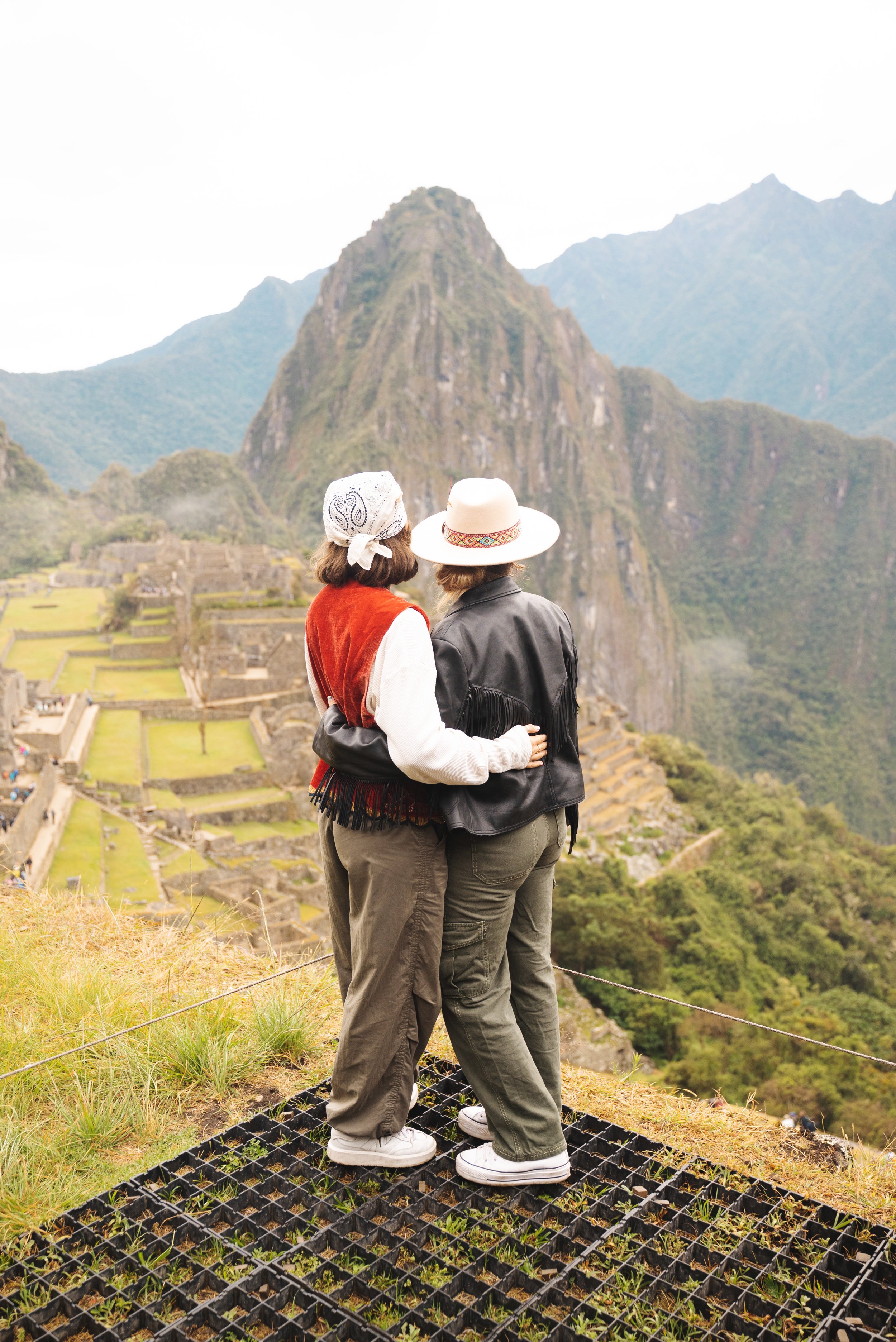 two girls hugging in front of machu picchu peru