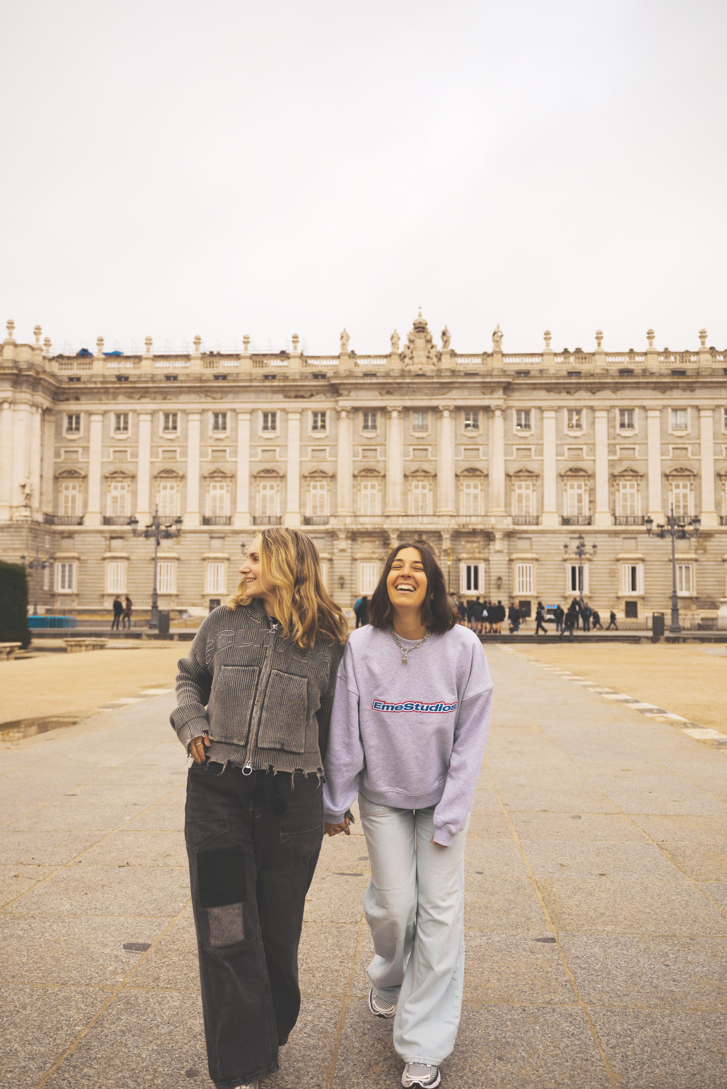 two girls walking in front of royal palace of madrid
