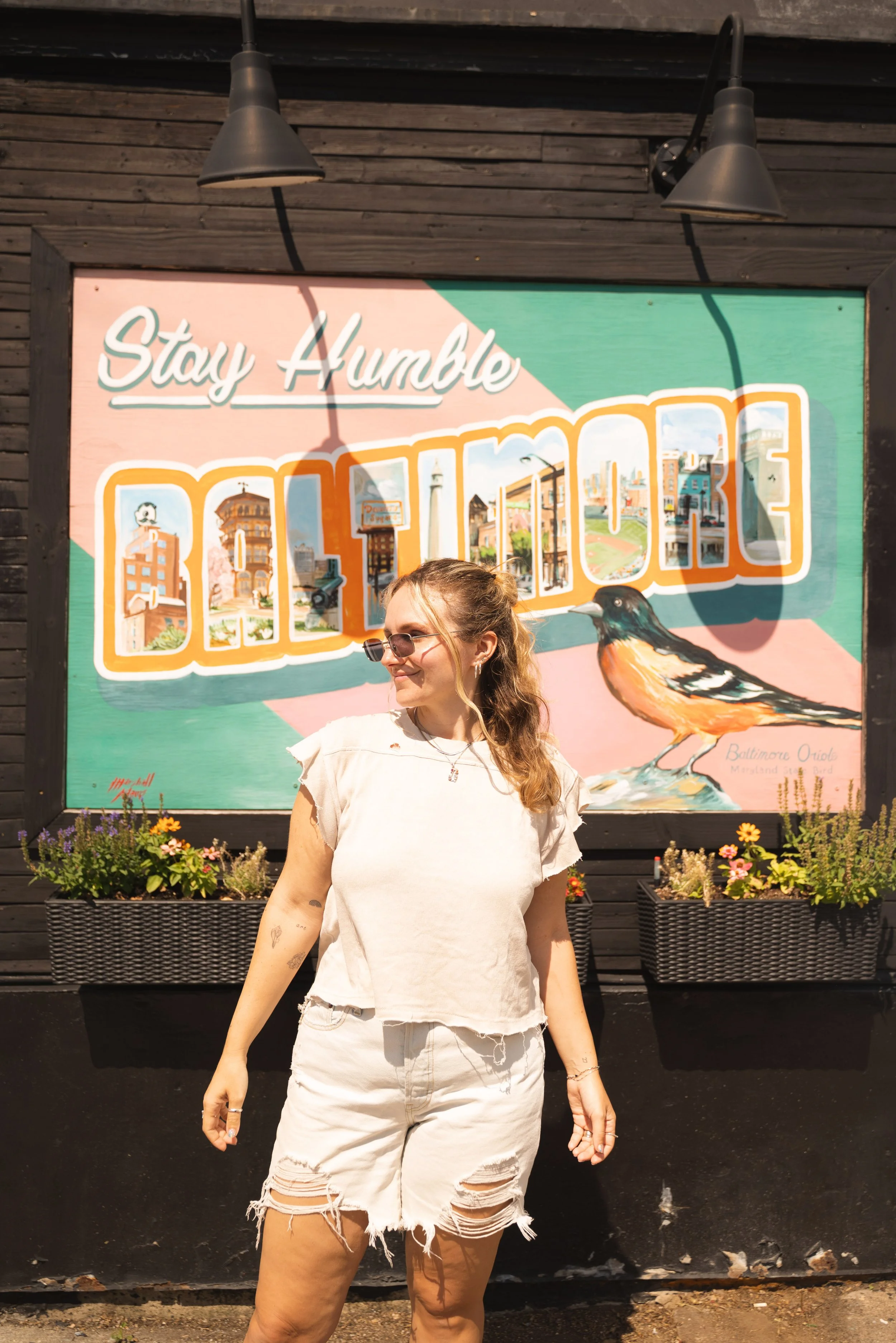 girl standing in front of stay humble baltimore sign