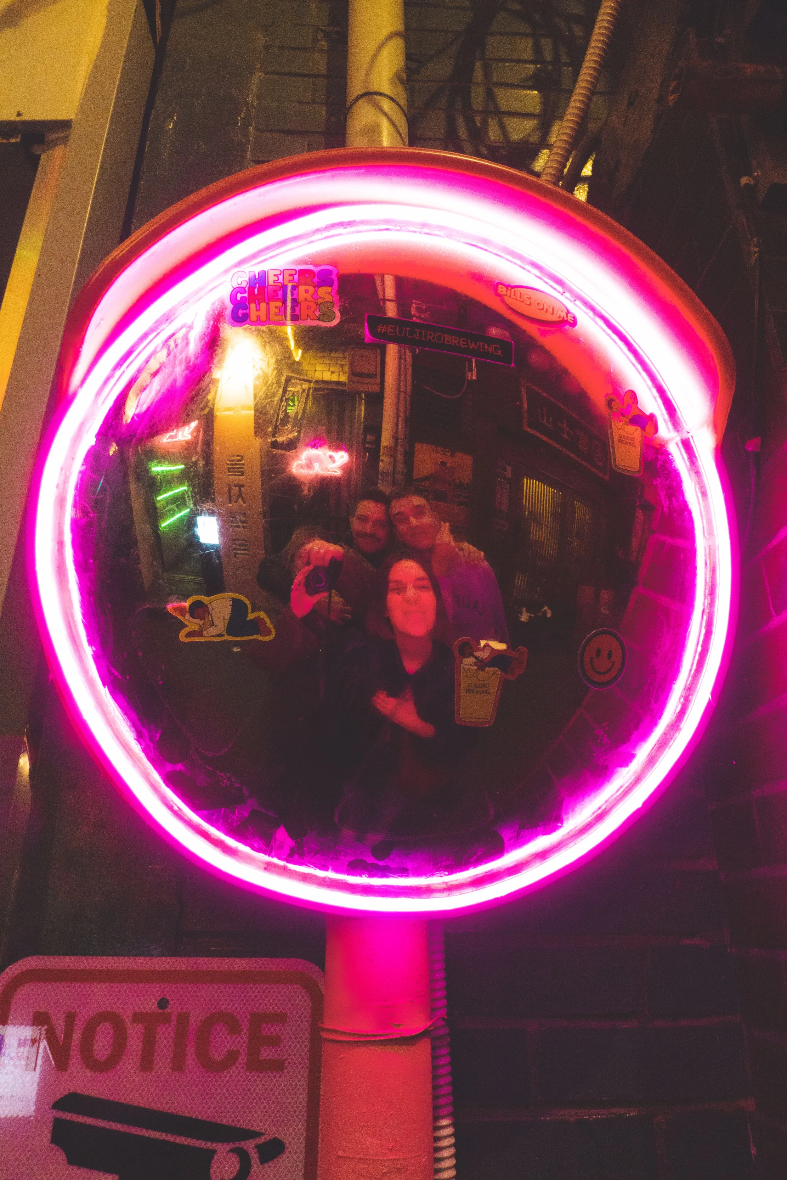 friends taking a picture in a neon mirror in euljiro seoul