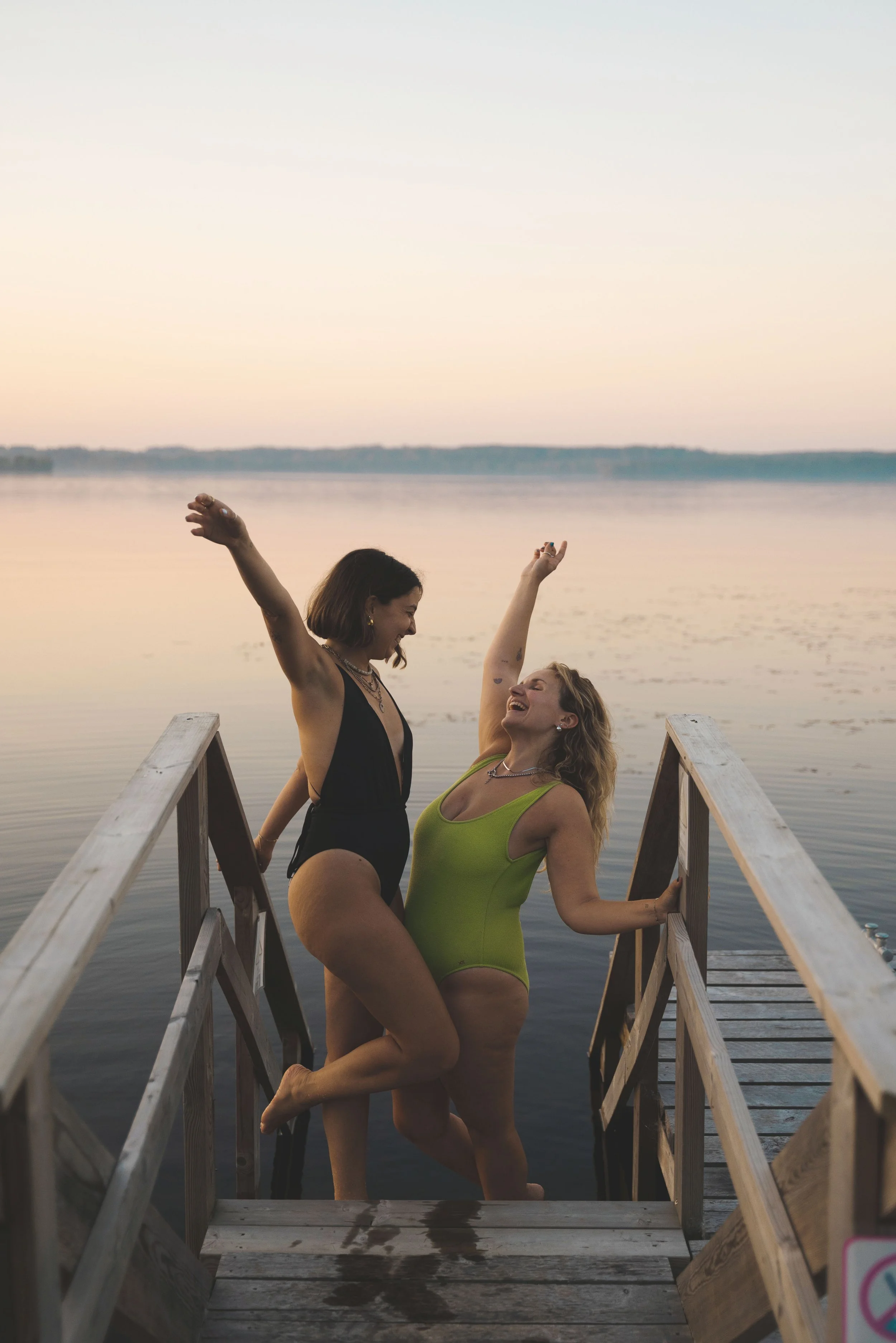 two girls standing on a lakeside dock at sunset at Tahlo Ventures finland