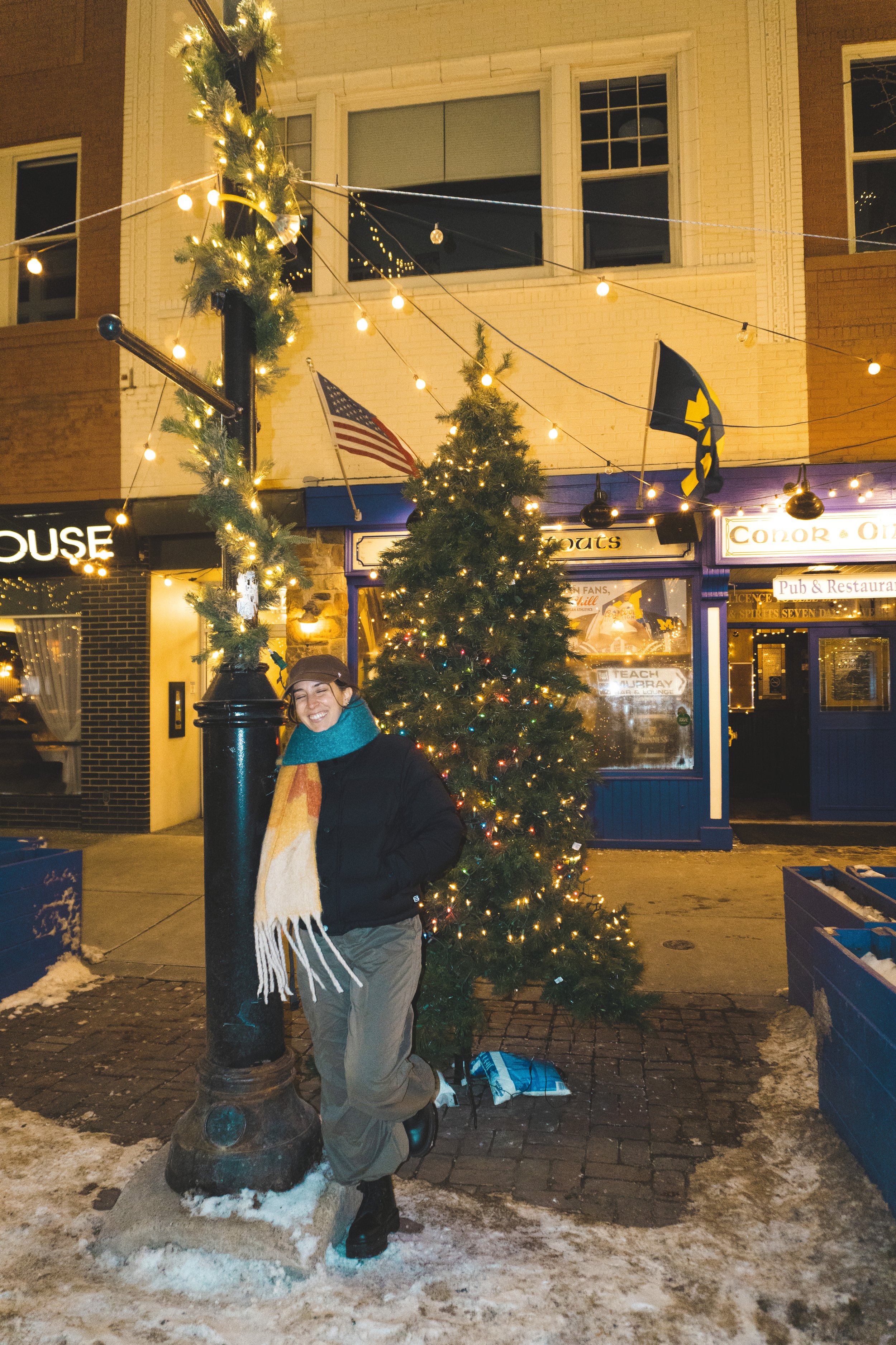 girl standing by christmas tree during downtown ann arbor midnight madness