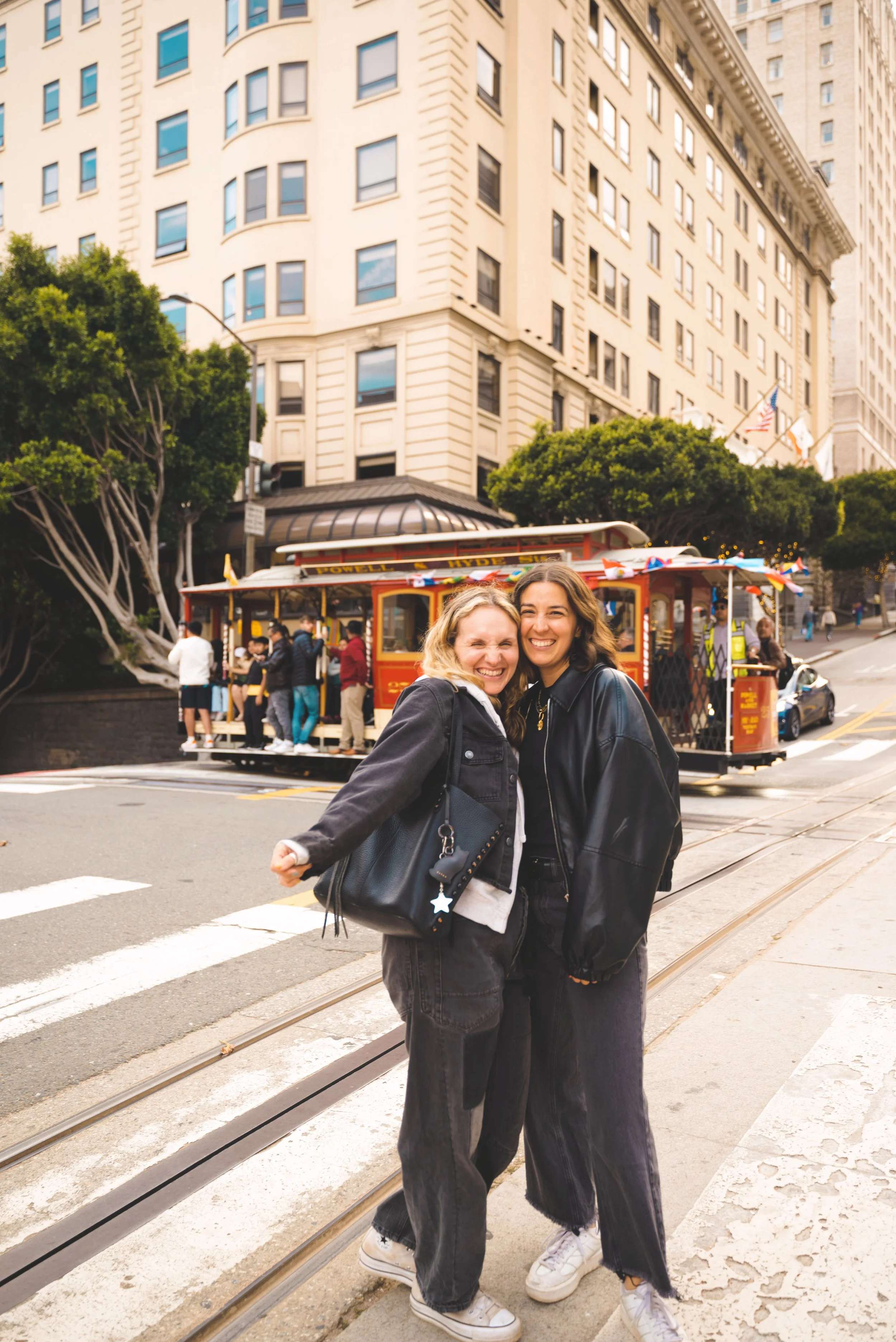 two girls standing in front of tram in san francisco
