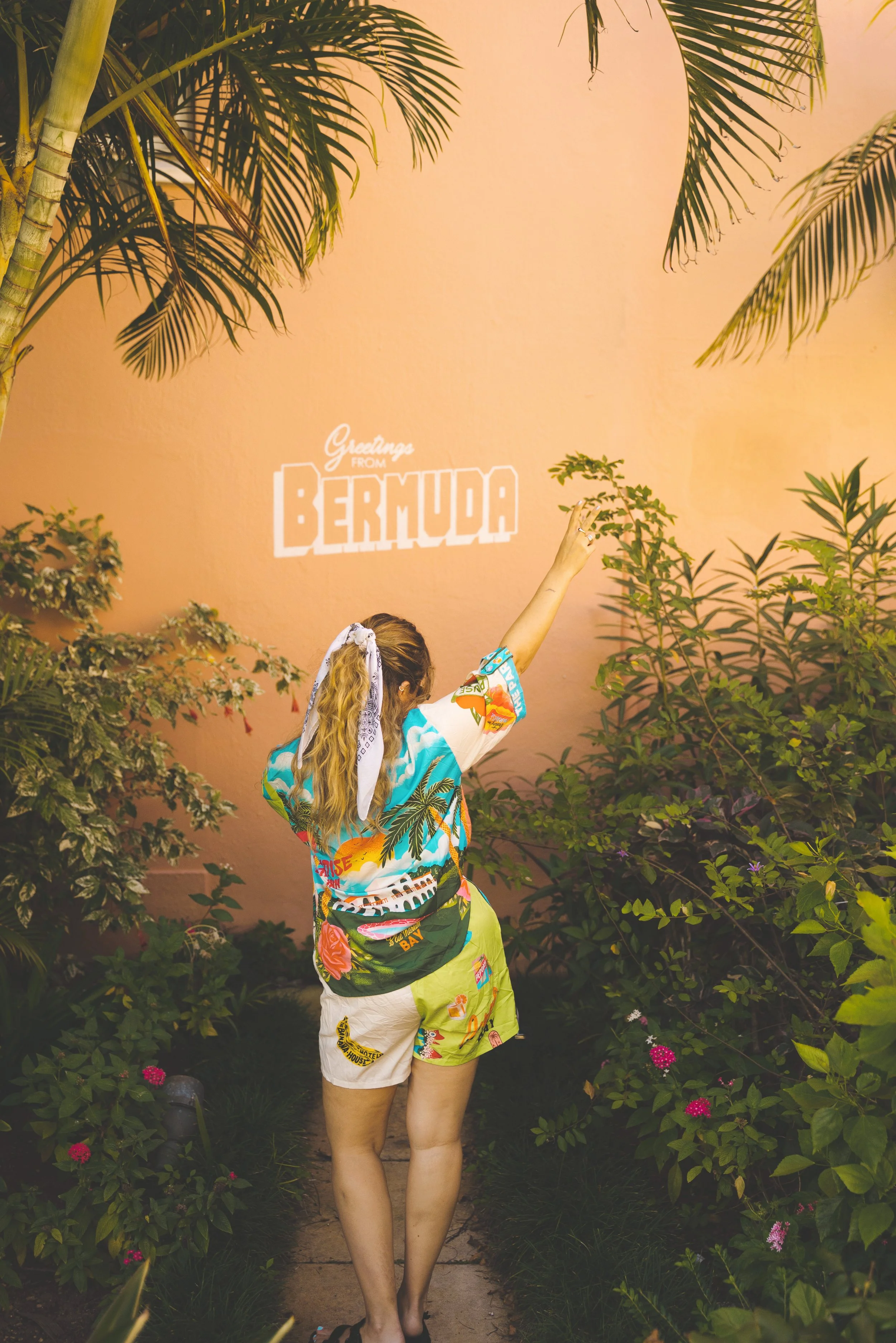 girl standing in front of greetings from bermuda sign at hamilton princess