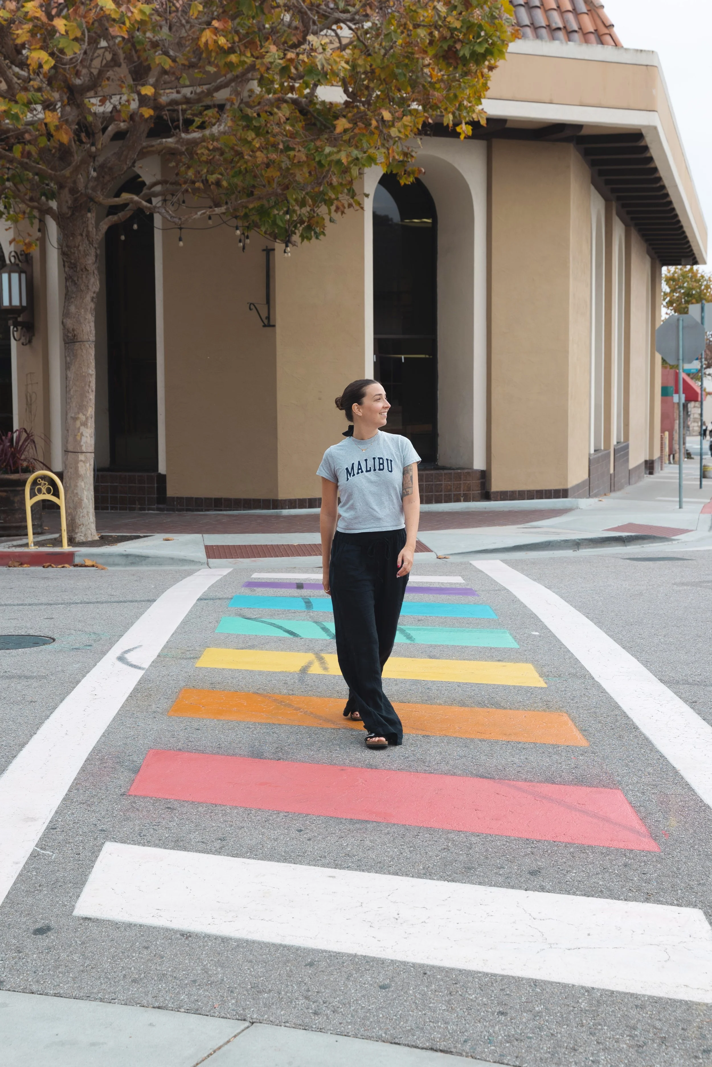 girl walking on rainbow crosswalk in monterey