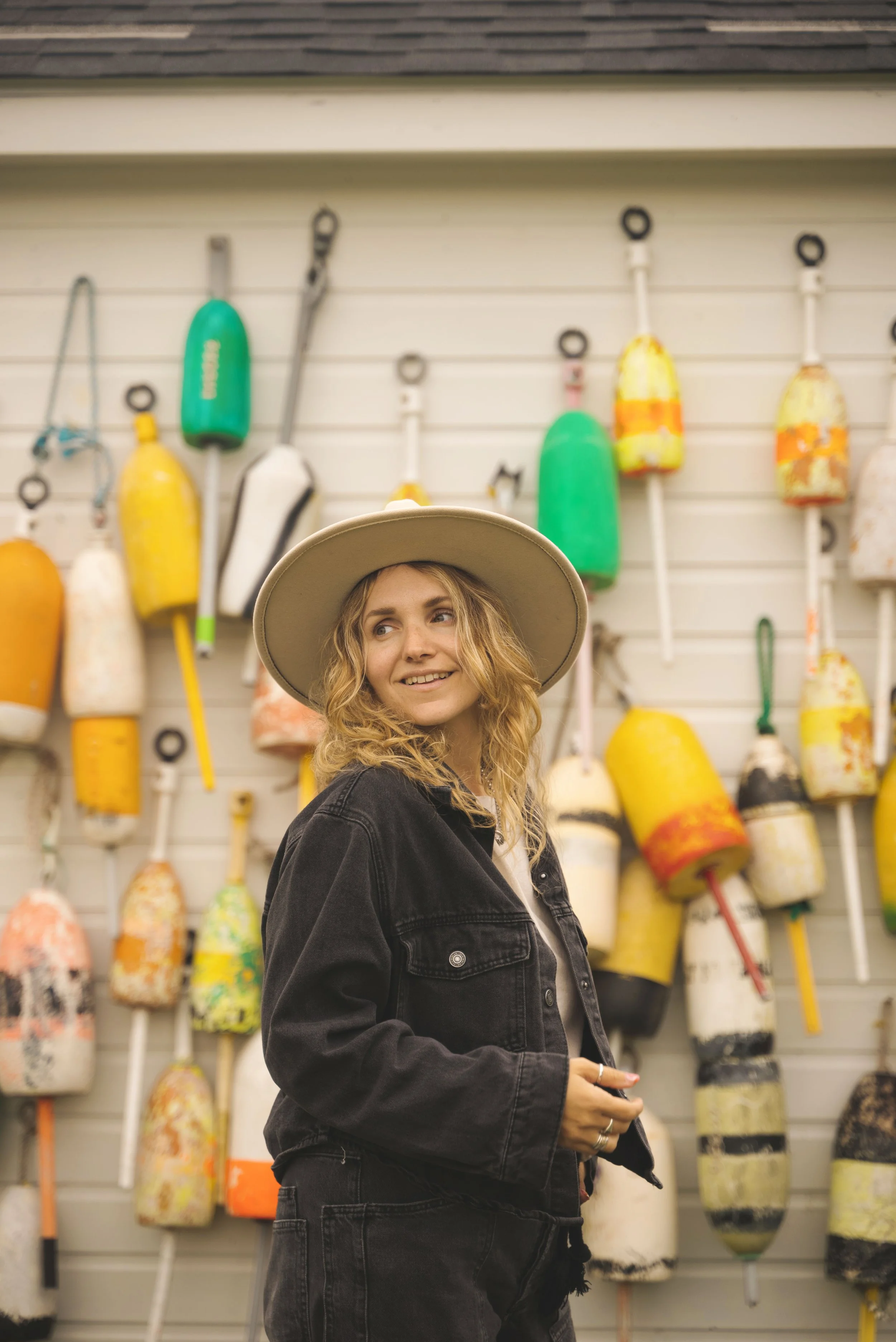 girl standing in front of colorful buoys bar harbor maine