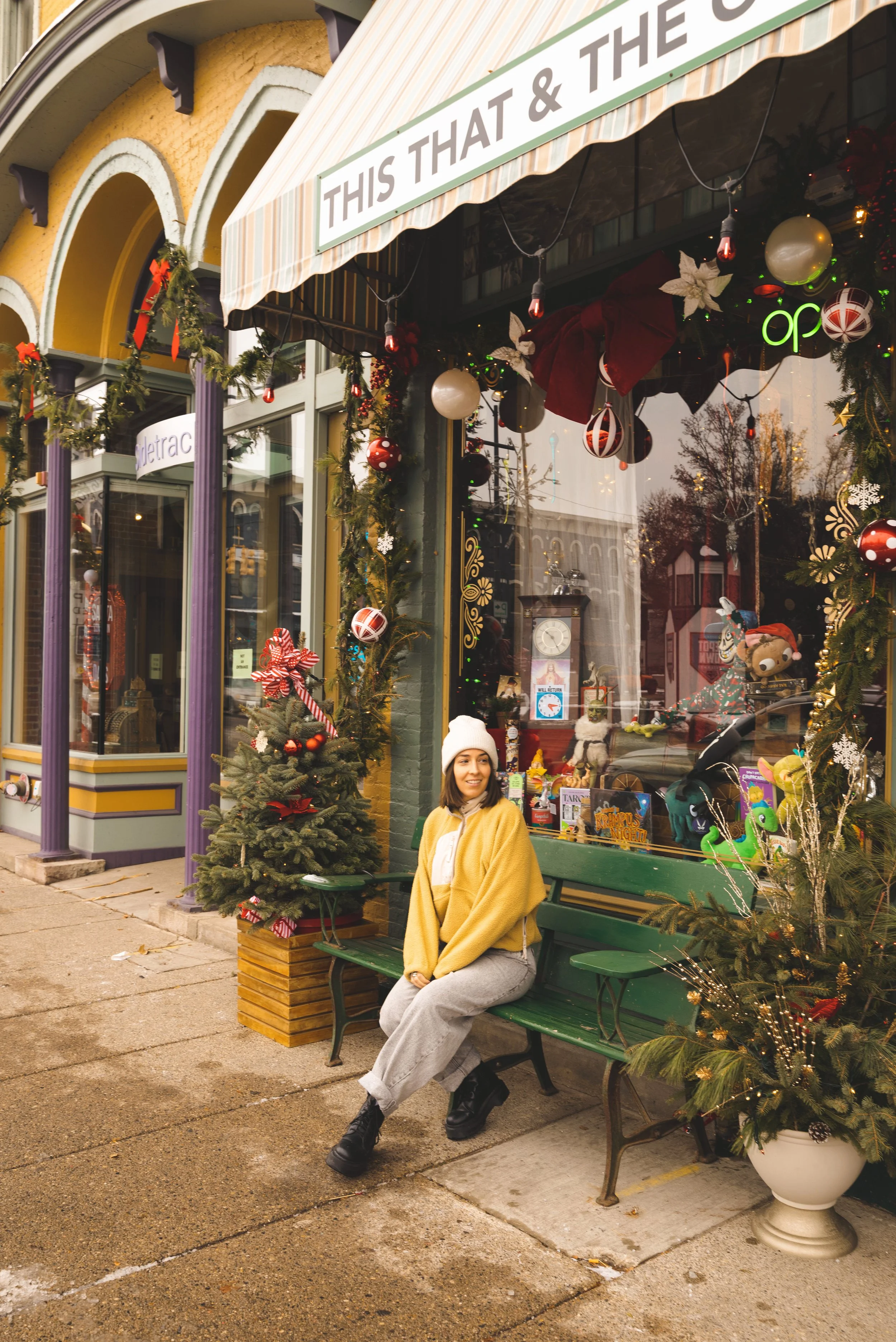 girl sitting in front of holiday decorated store window in depot town ypsiltanti