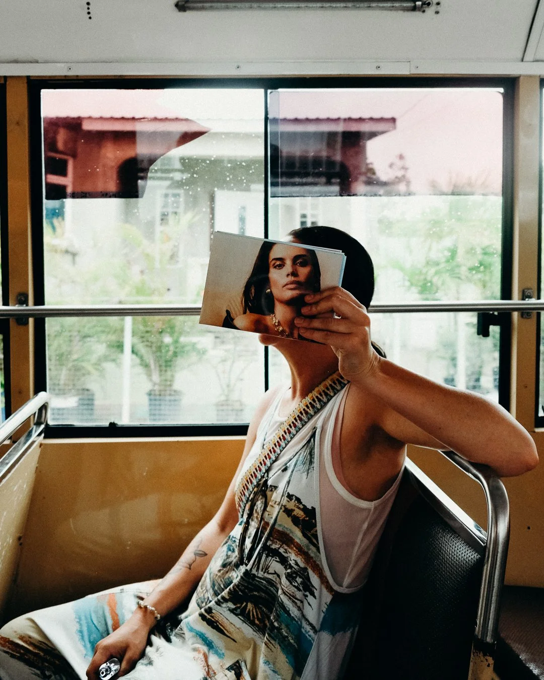 A lady on a bus holding a magazine to her face traveling to Bridgetown in Barbados