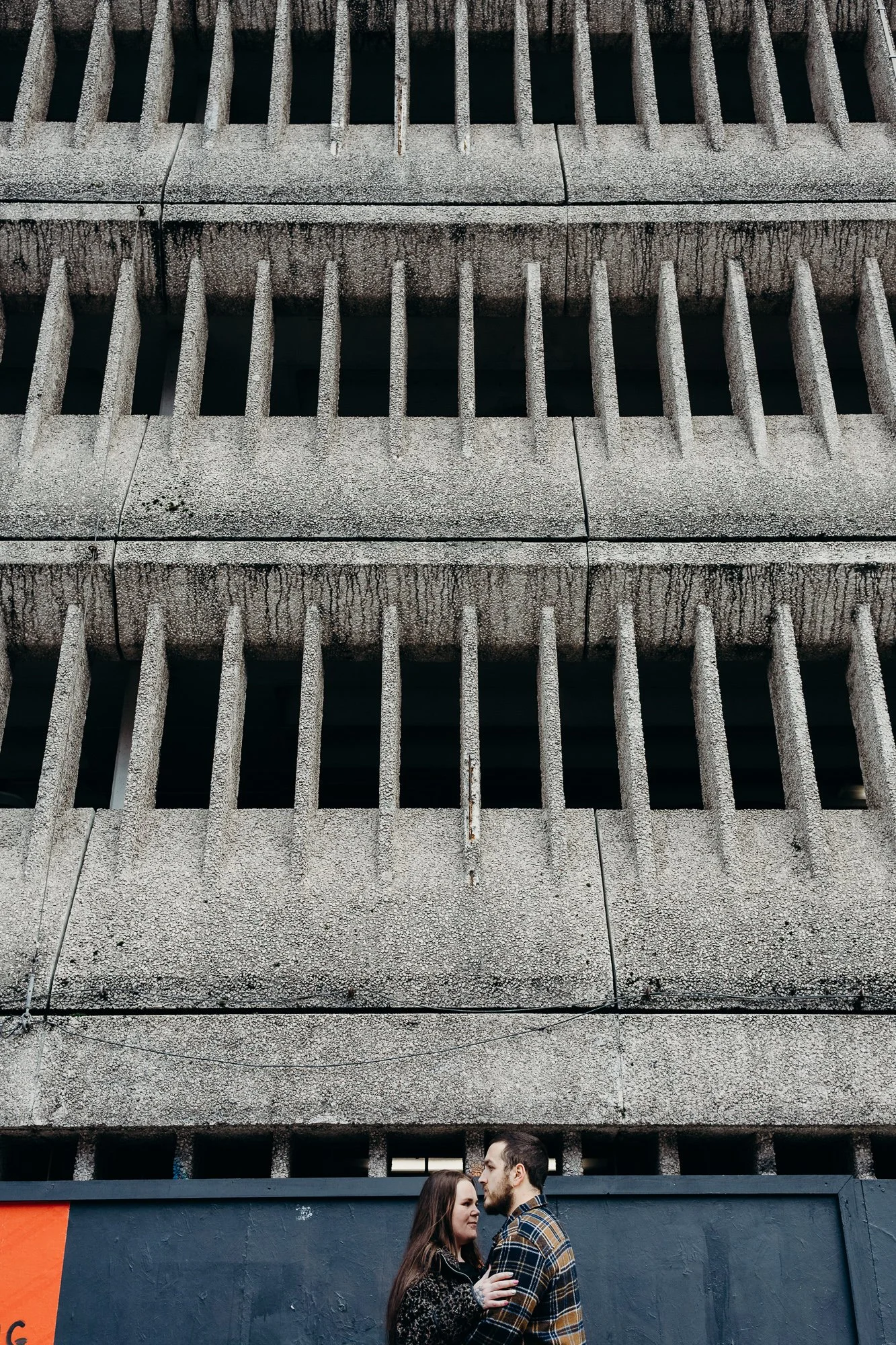 A couple embracing outside a car park in Cardiff city centre for an engagement photo 