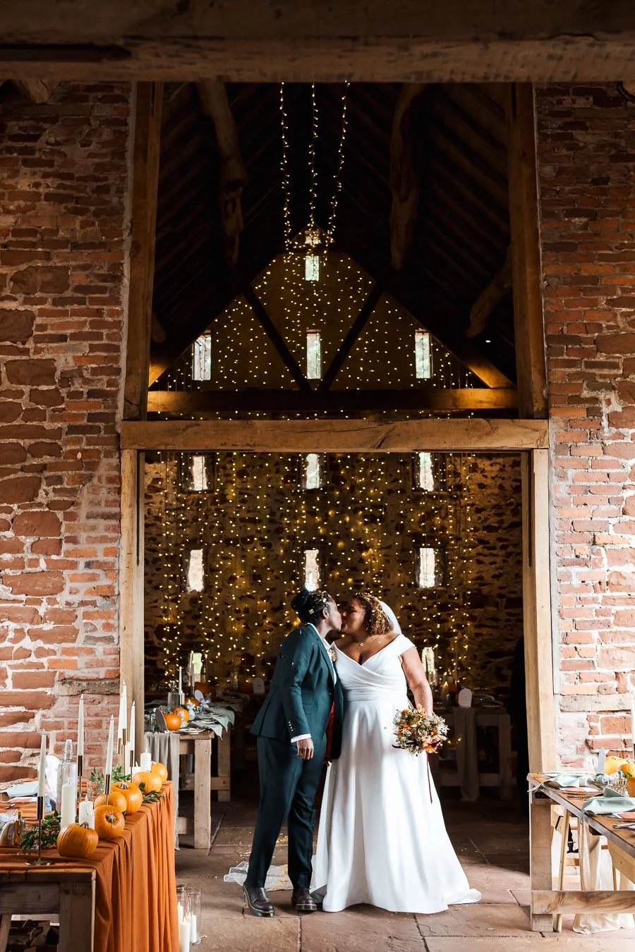 couple kissing in rustic barn wedding venue decorated with string lights, bridgnorth