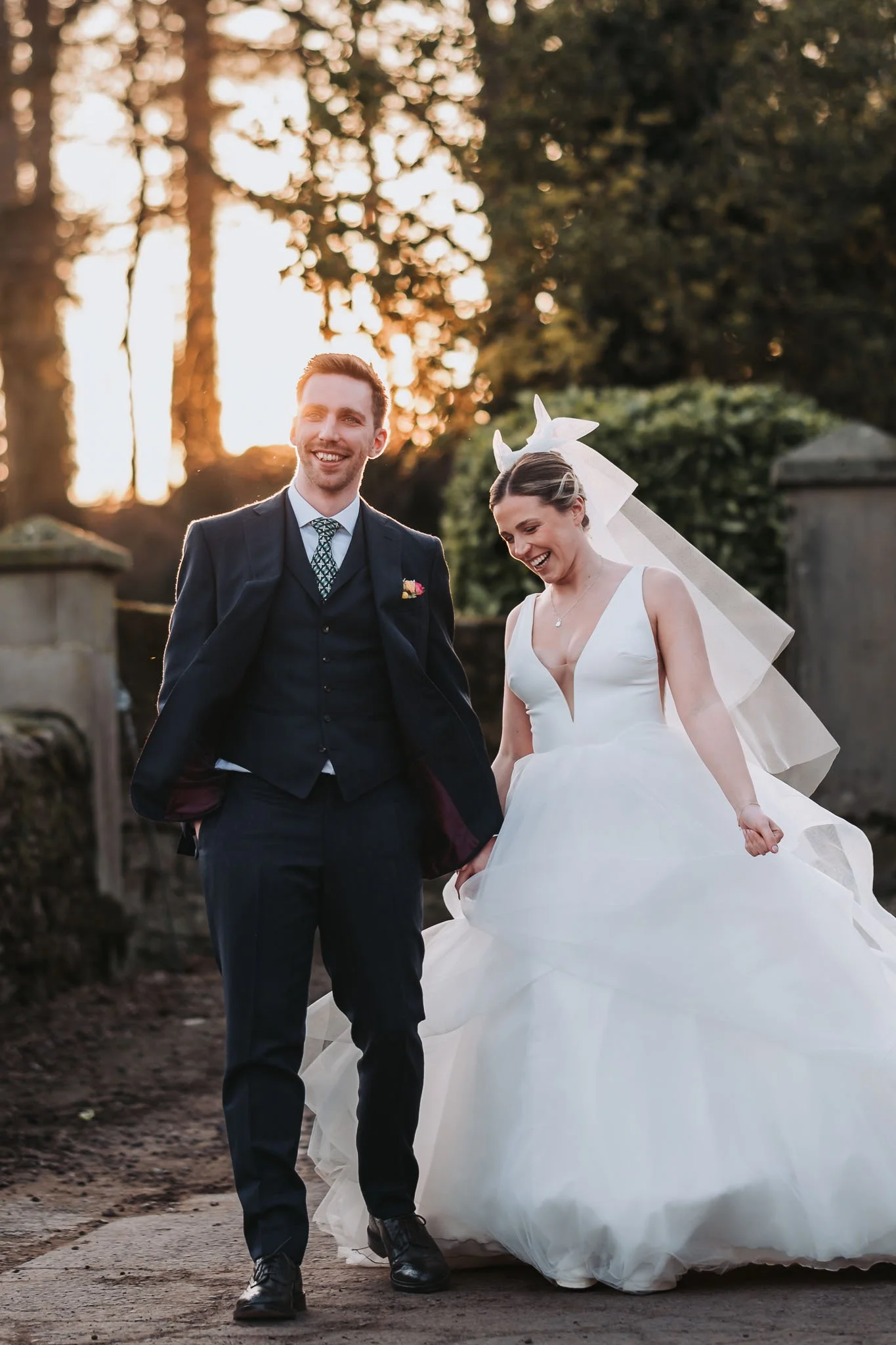 Bride and groom walking under a canopy, surrounded by friends throwing confetti at an outdoor wedding celebration.
