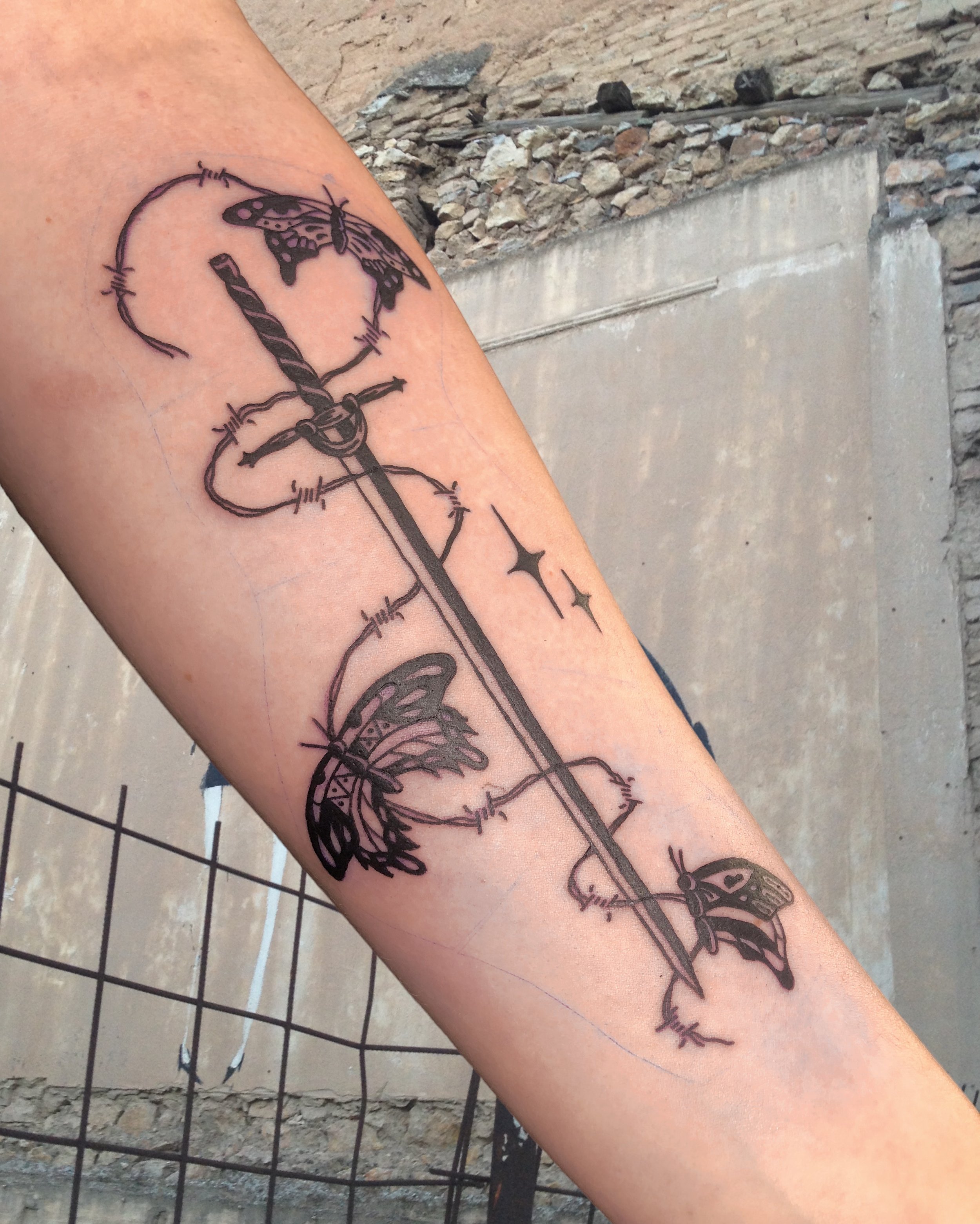 Composition of a sword with barbwire and butterflies tattooed inside lower arm.JPG