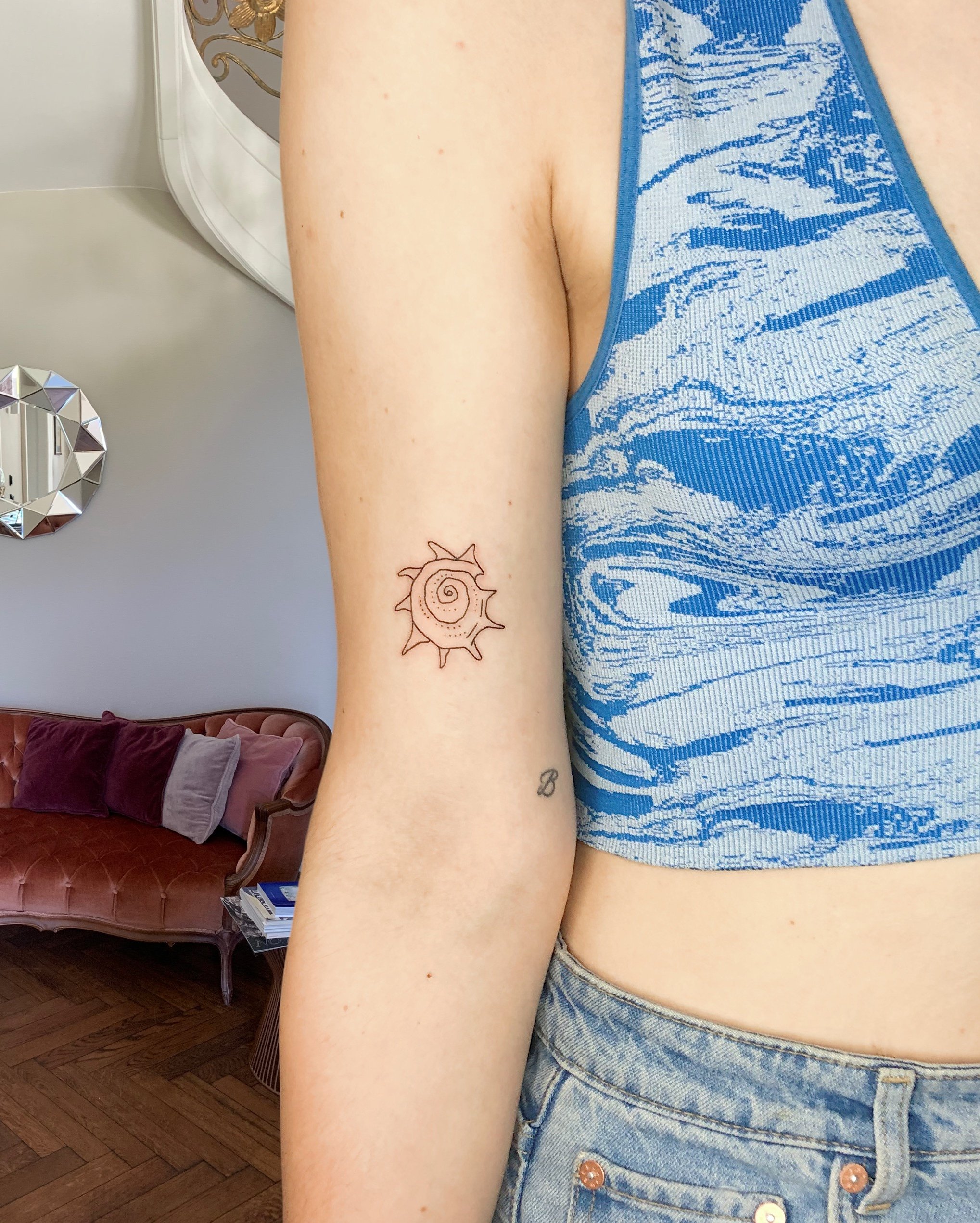 Small simple shell linework tattoo on upper arm.JPG