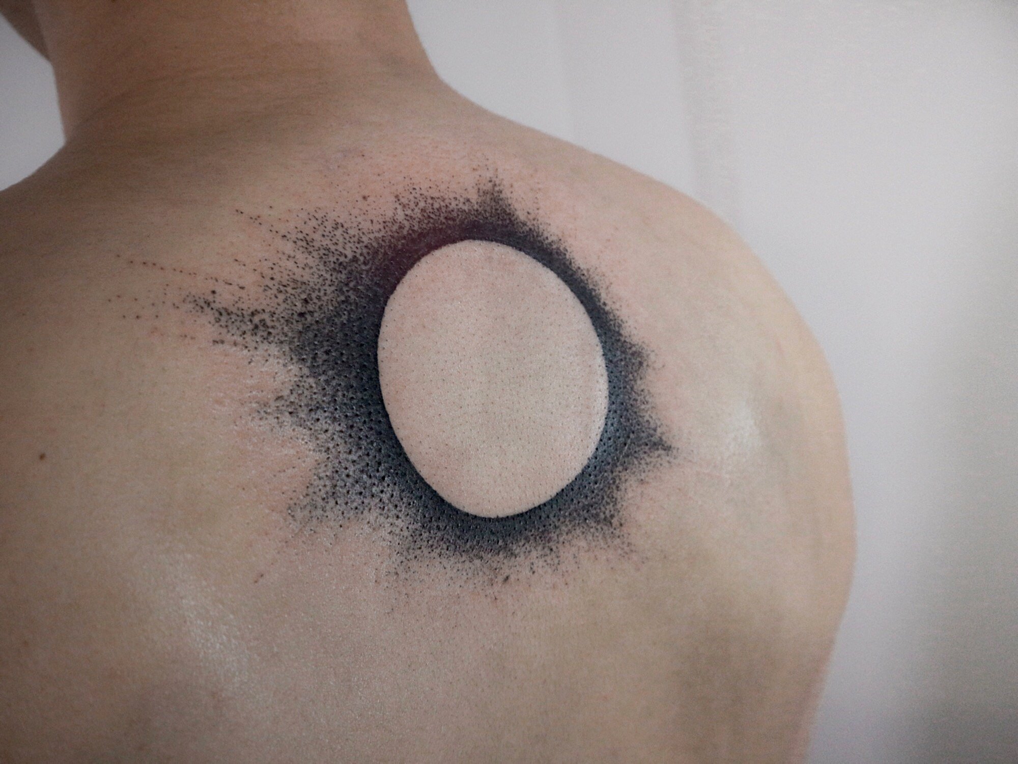 Negative space making a circle tattooed on the back by boy.brush.ttt.jpg