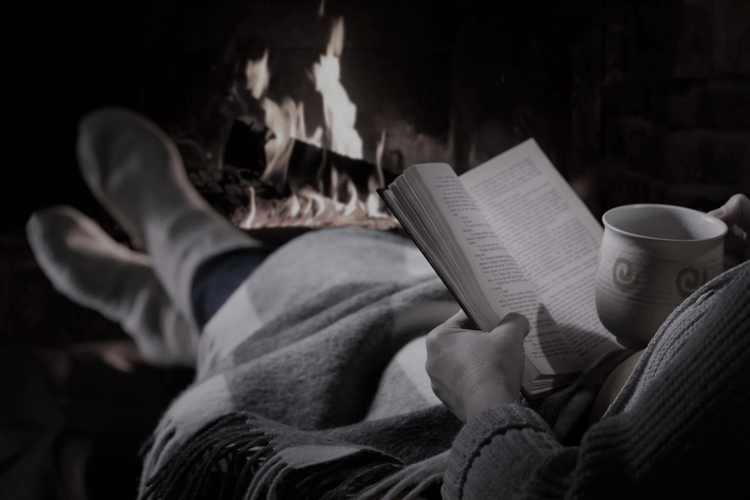 Woman reads book near fireplace