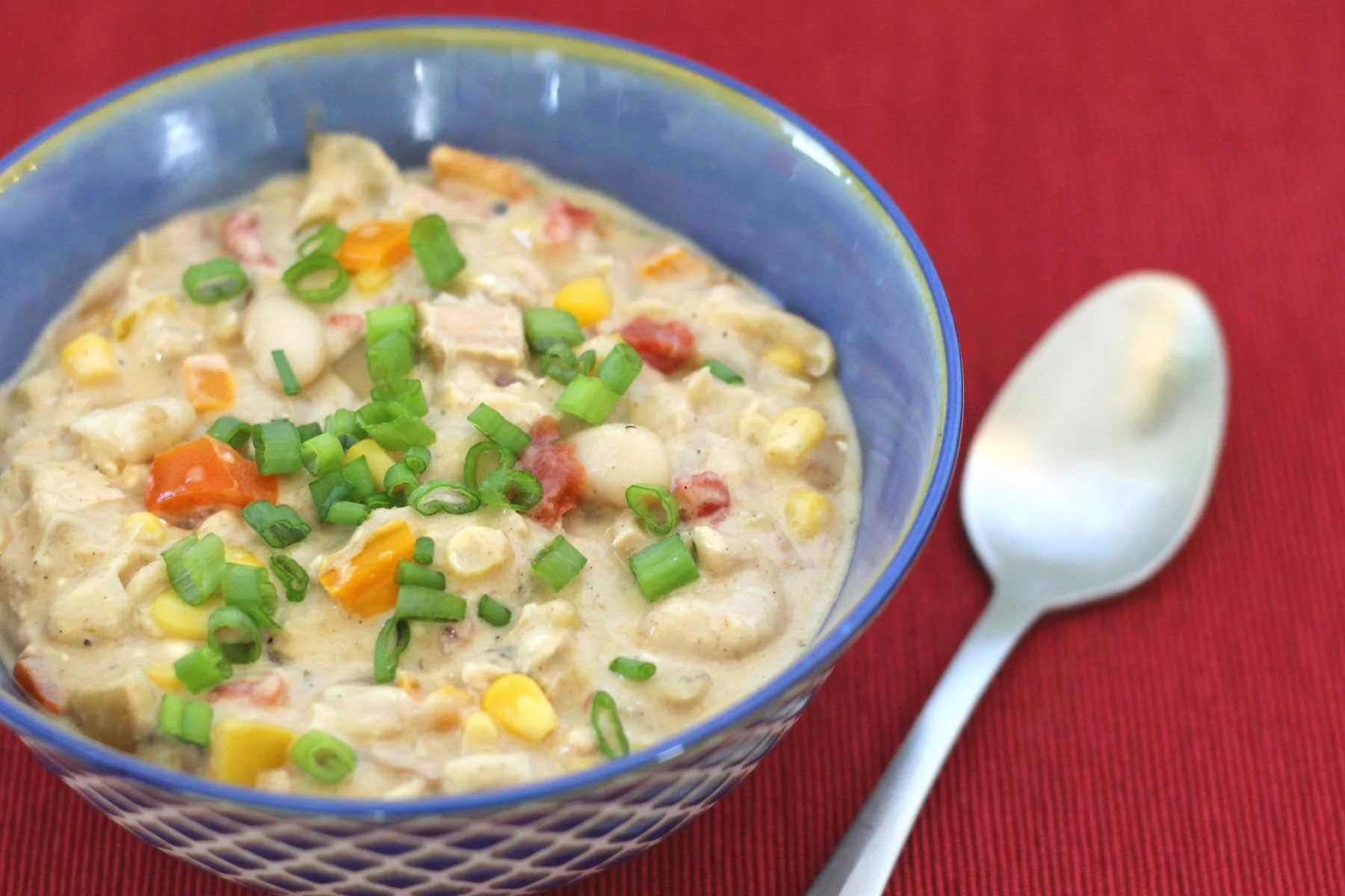 Bowl full of white chicken chili made with rotisserie chicken, bell peppers, corn, white beans, diced tomatoes with green chiles, and finished with tangy cream cheese.