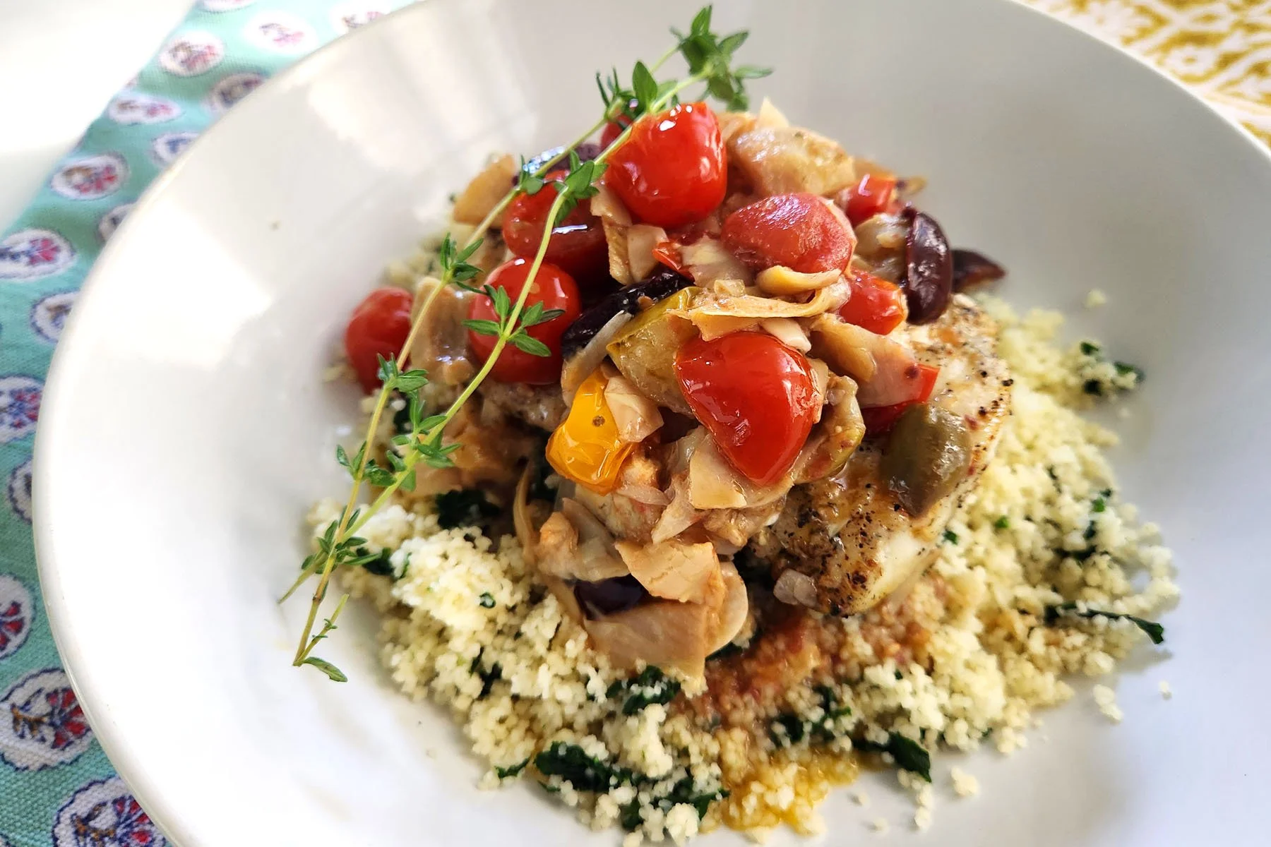 Warm tomato, olive, and artichoke olive oil sauce over wild pacific cod on a bed of couscous with spinach.