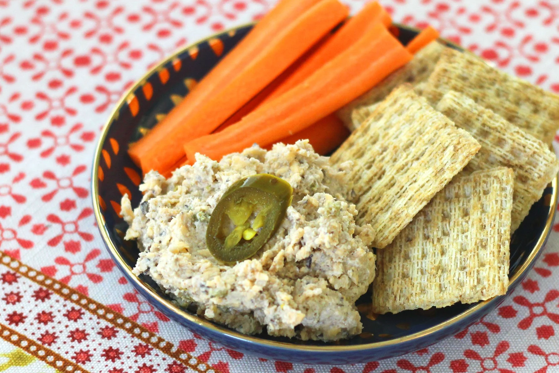 Satifying snack plate with black-eyed pea jalapeno cheddar spread, carrot sticks, and crackers.