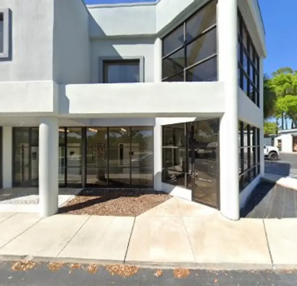 Modern two-story white building with large framed glass windows, sidewalk in front, 1064 W Hwy 50 Clermont FL 34711 suite 205 