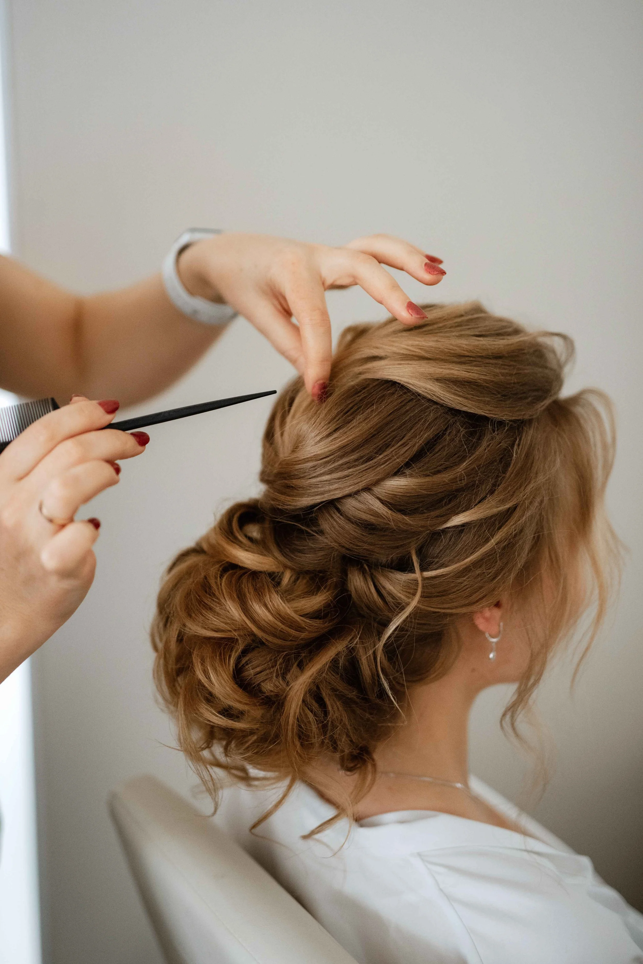 A stylist combing through a client's elaborately braided hair