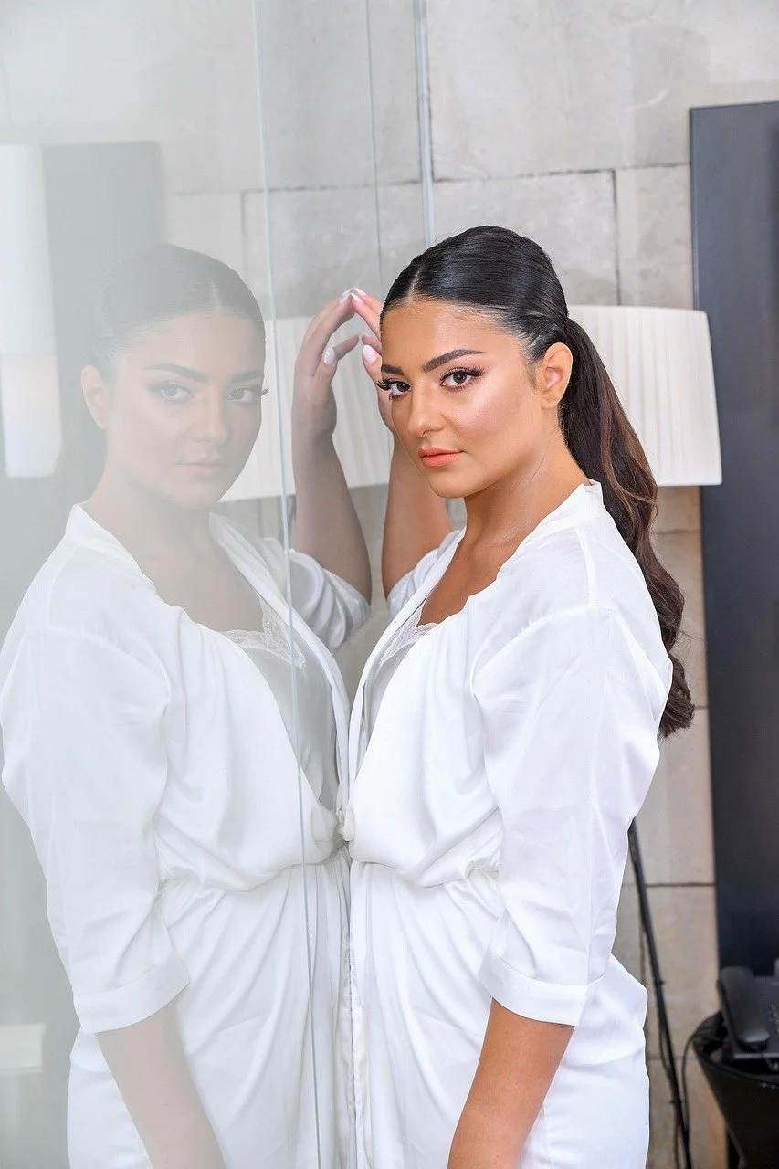 A woman in white posing inside a hotel room
