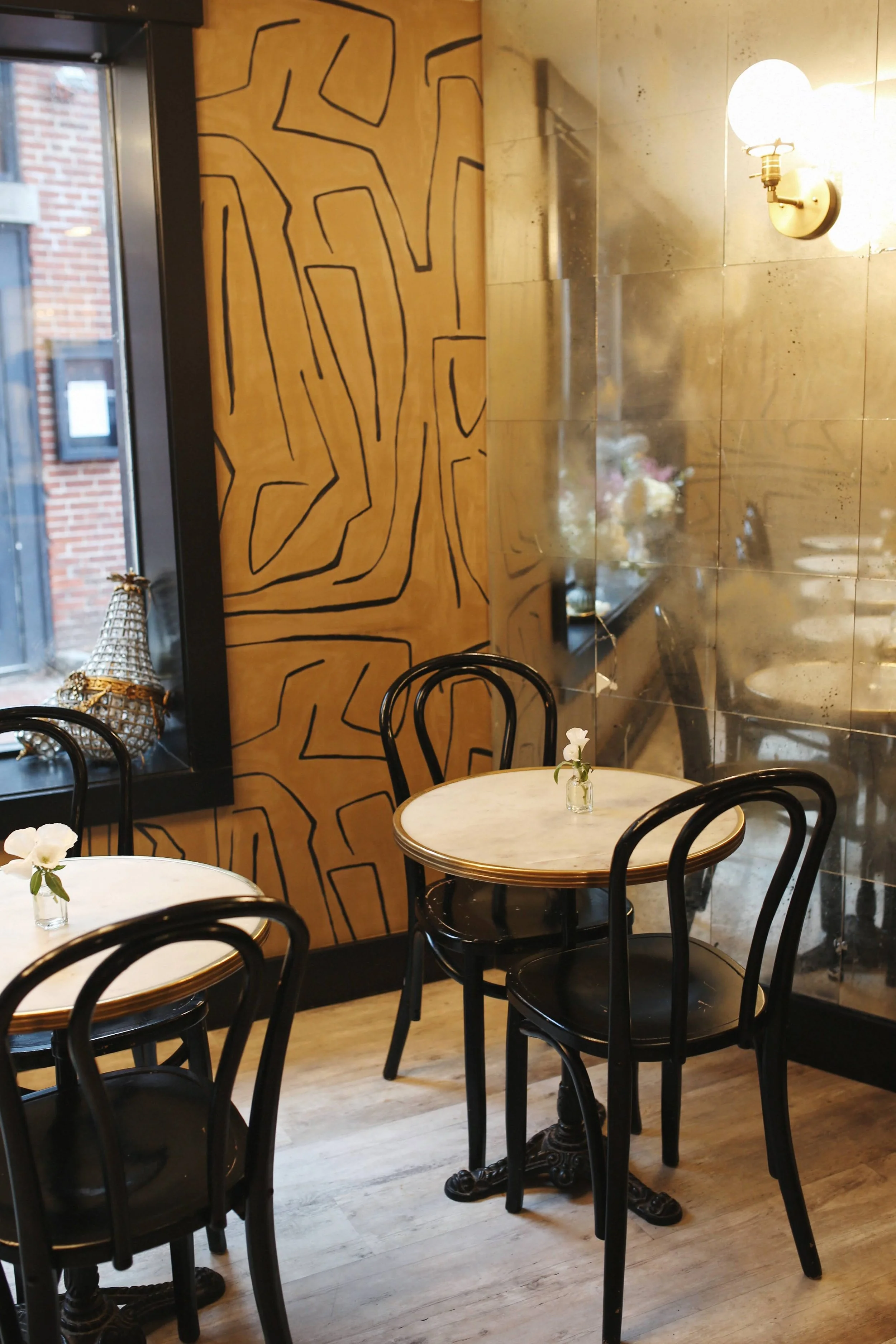 Charming interior of Elephantine Bakery’s café in Portsmouth, New Hampshire, featuring bistro tables, chairs, and an old-world mirrored wall