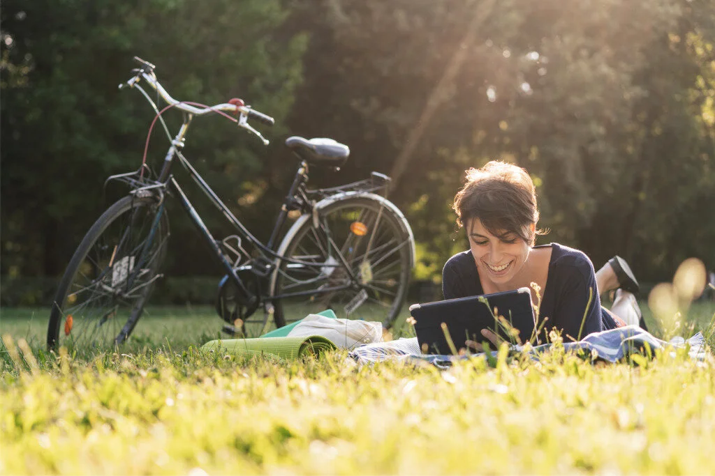 young-adult-woman-reading-an-ebook-at-a-public-park-picture-id1002877810.jpg