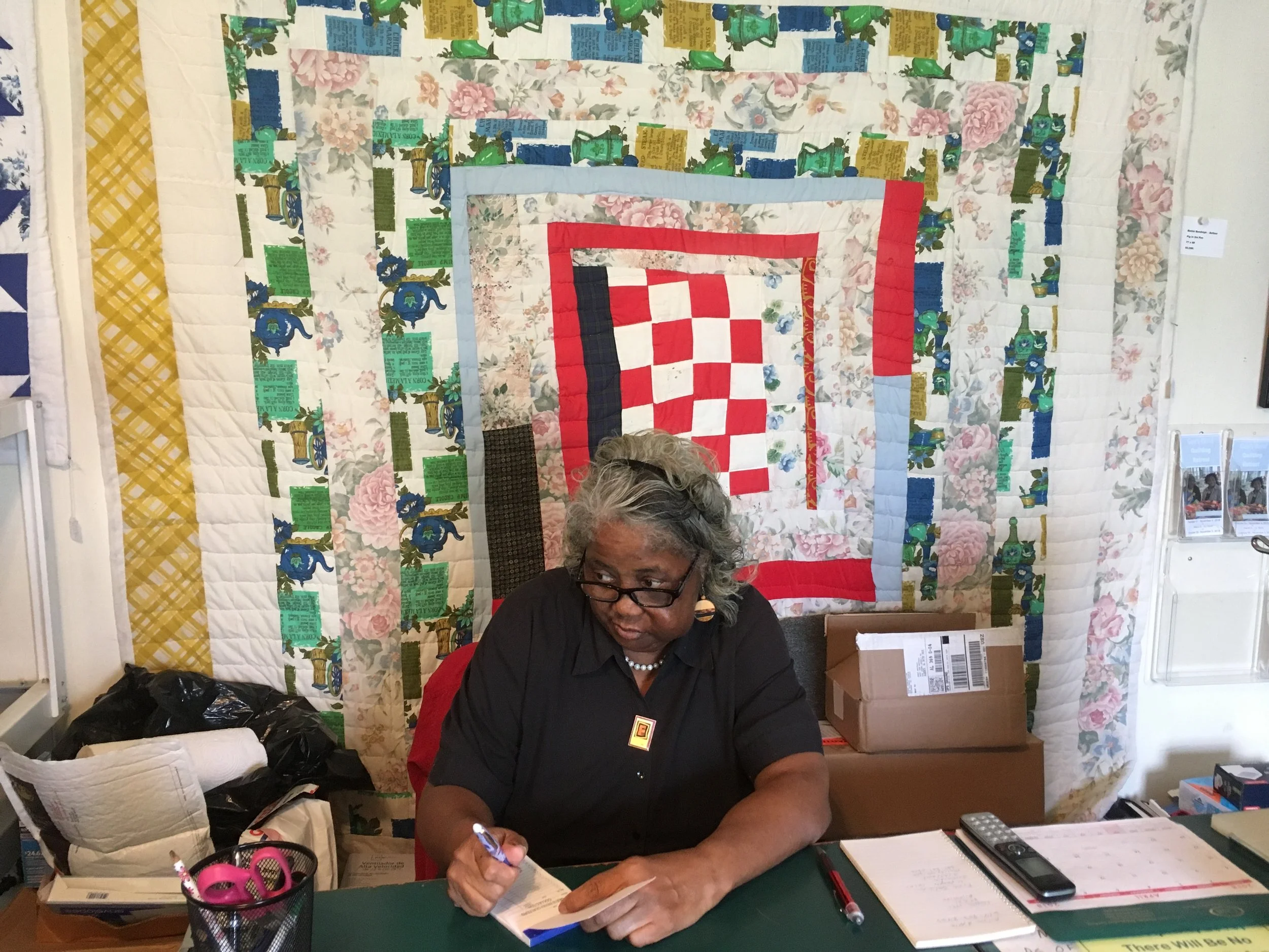 Mary Ann Pettway, Director of the Gee’s Bend Quilt Collective. Sitting in front of a quilt made by Bettie Bendolph-Seltzer.