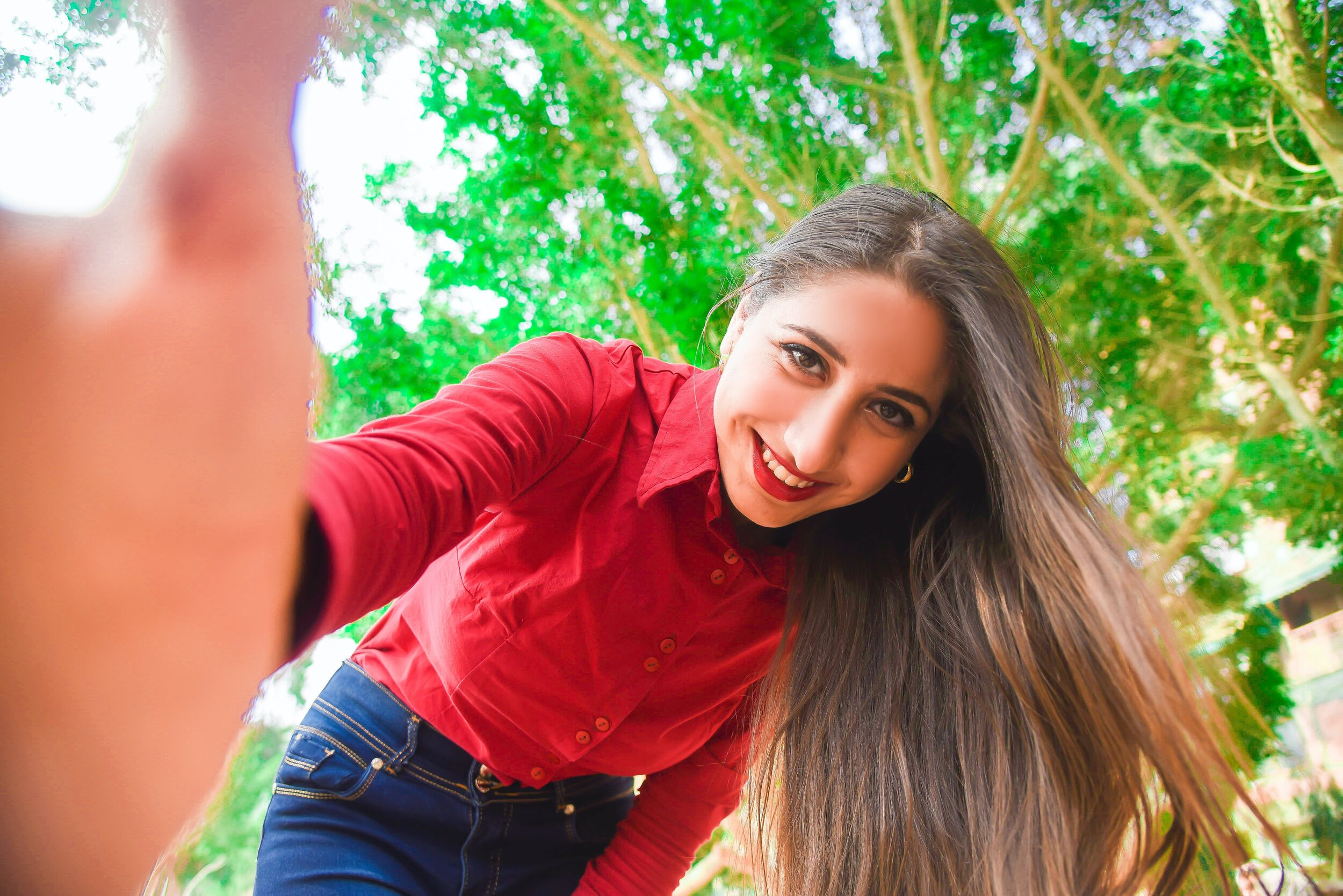 smiling-woman-in-red-shirt-and-blue-jeans-taking-selfie-674685.jpg