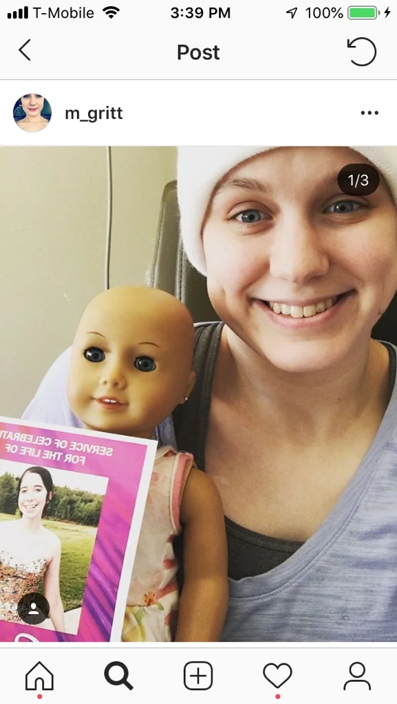 Sweet Molly Gritt holding a photo of Bella and Bella's bald doll that she lovingly received for her journey in memory of Bella.