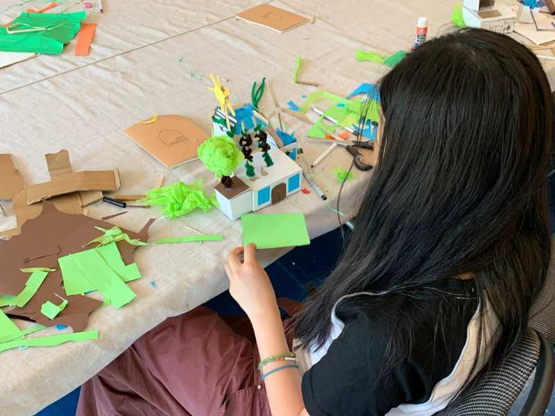 Young child building a 3D model of an eco-building using recycled materials