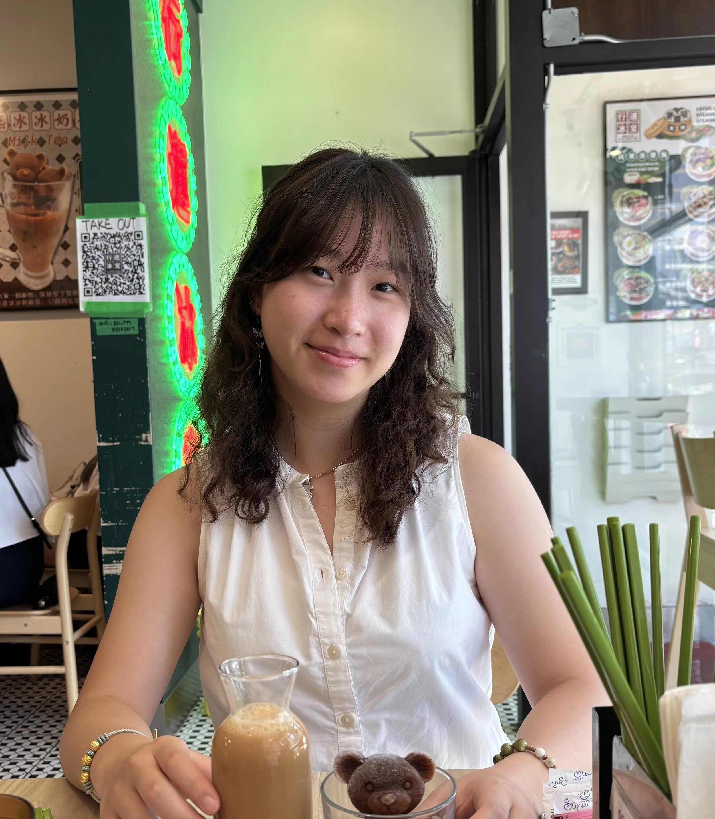 A woman sitting at a table with green bamboo stalks visible on the table in front of her.
