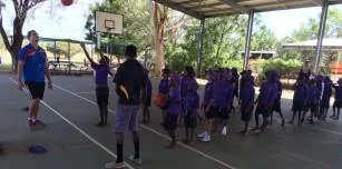 Jarrah Phillips (left) and Tristan McCarthy (right) run a basketball shooting drill with the girls and boys from Bayulu Community School.