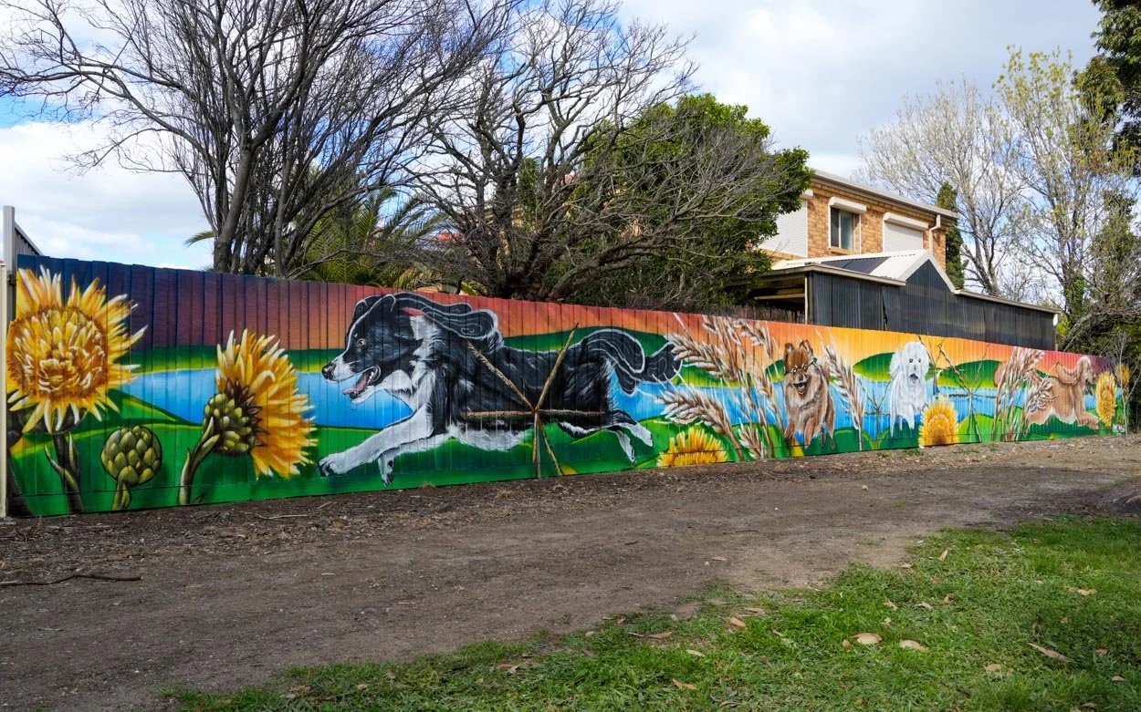 Sydenham Basin Reserve dog park mural by Melbourne mural artist Lukas Kasper for Brimbank City Council, featuring local flora, waterways, and neighborhood dogs.