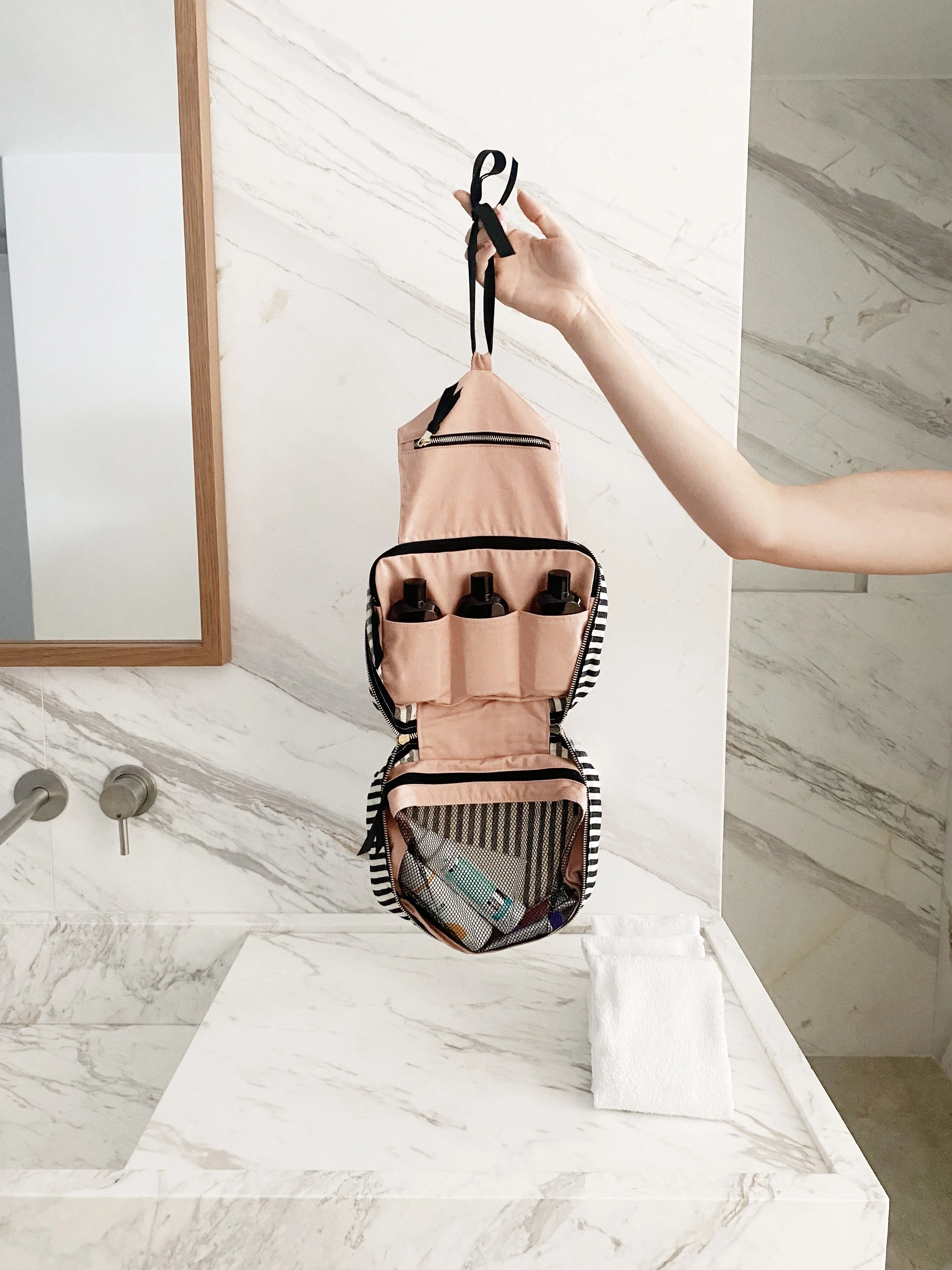 Travel toiletry bag with bottles and skincare organized in compartments