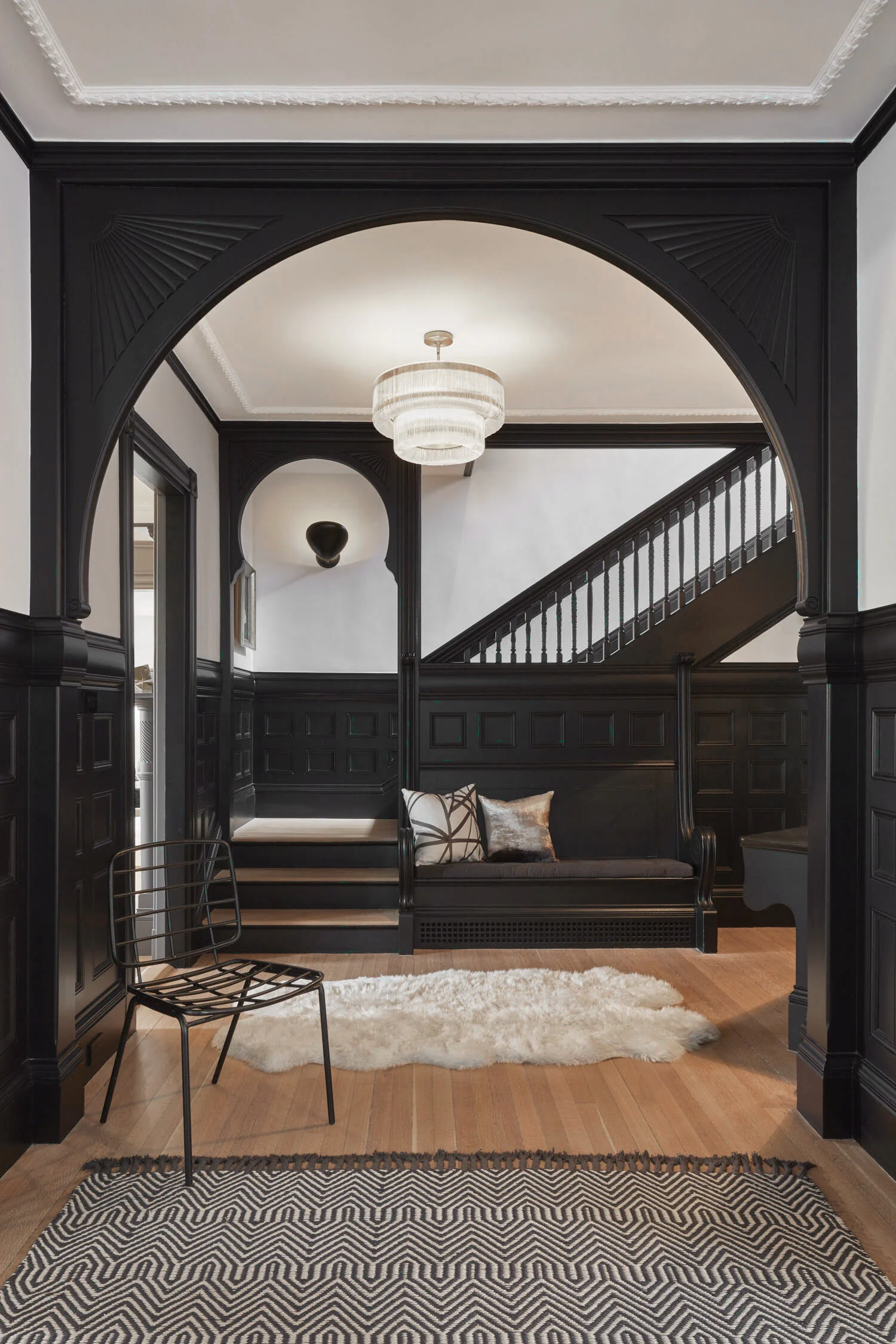 Updated ornate woodwork in the entryway of a historic home that also features contemporary lighting fixtures