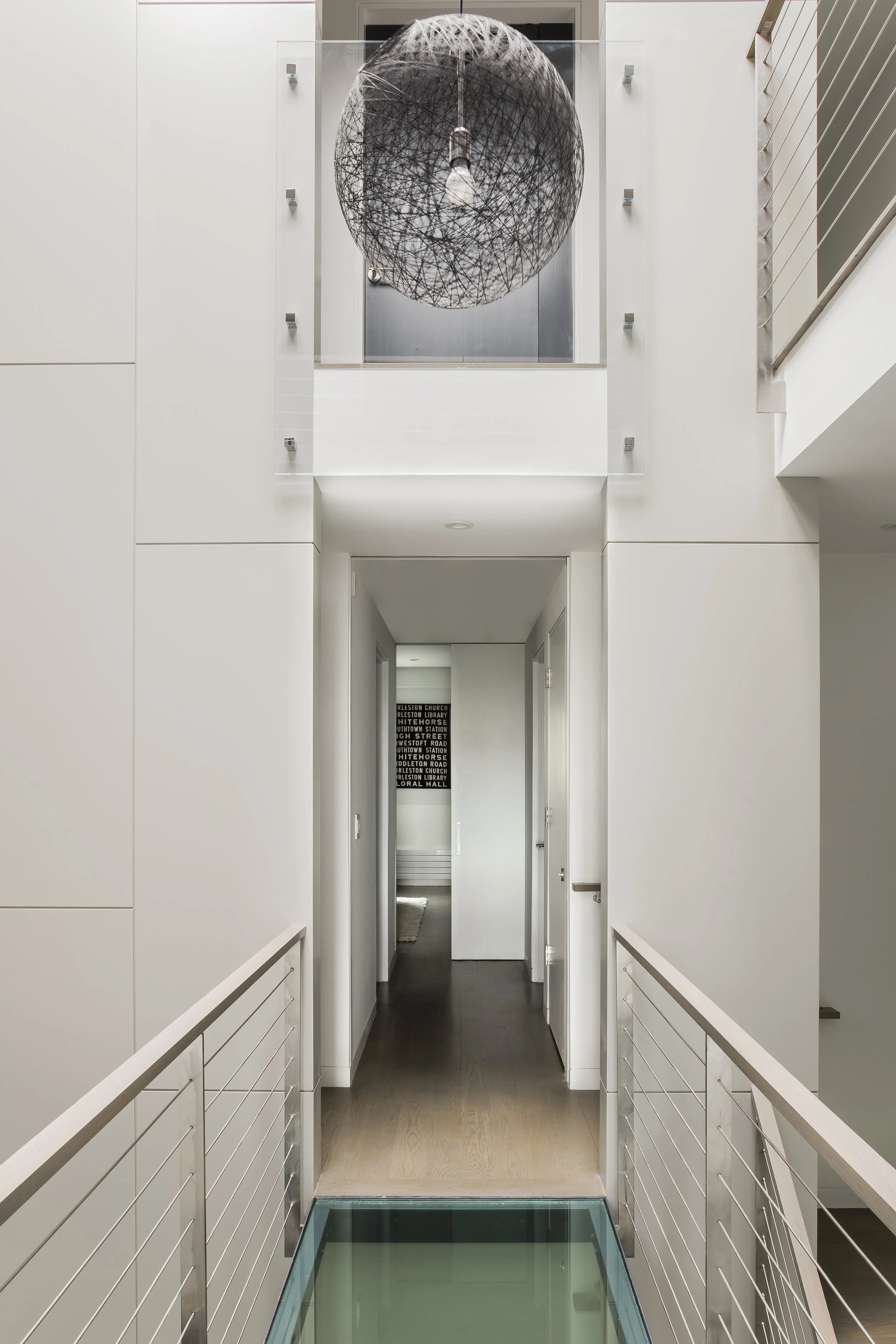 Glass bridge across a central stairwell at a renovated townhouse in Boston