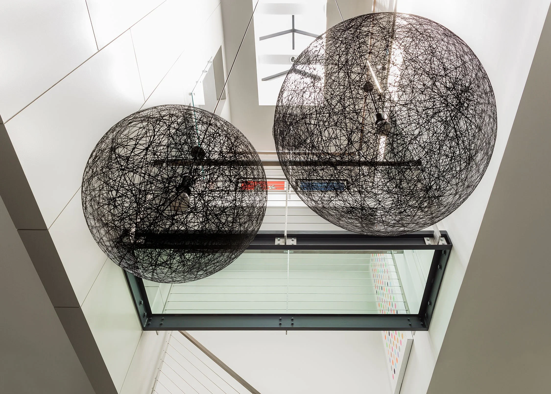 A three story atrium space in a Boston townhouse featuring a glass bridge and large pendant lights by Moooi (Copy)