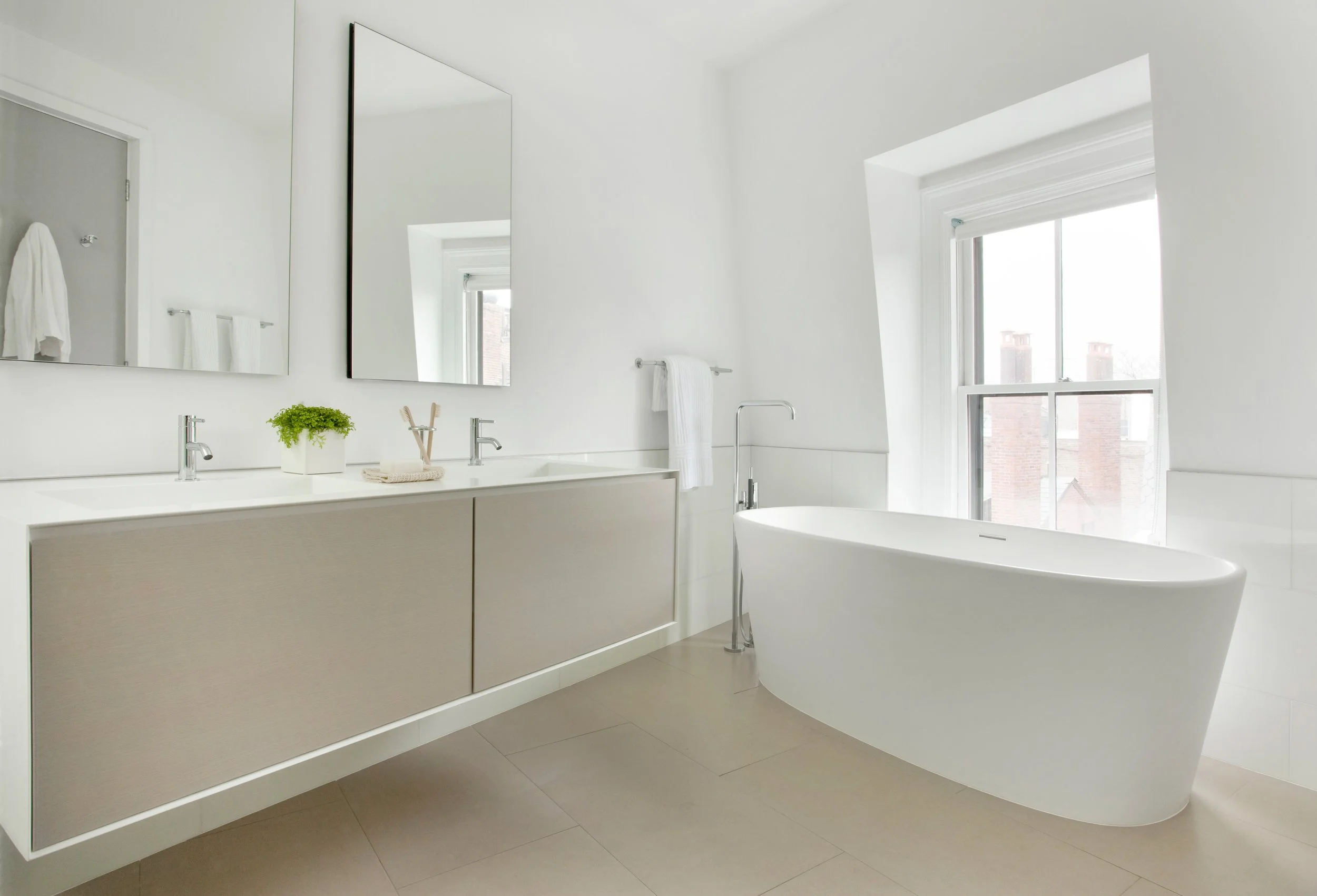 A modern floating vanity and freestanding bathtub in a minimalist white room