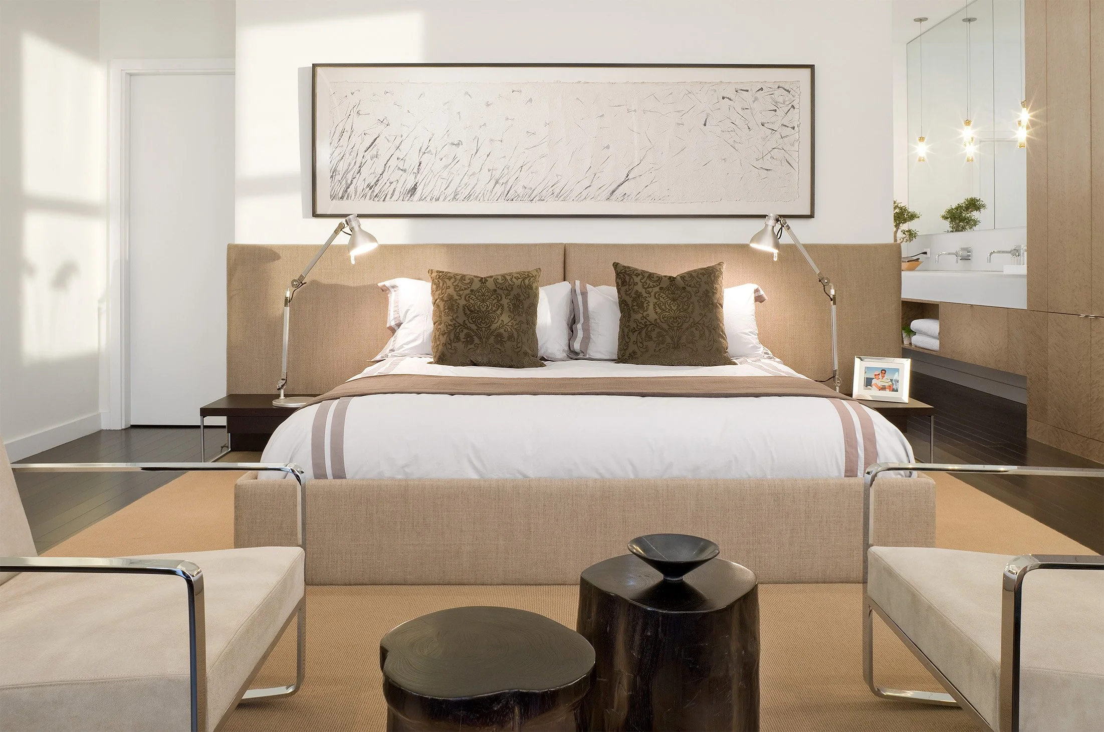 Contemporary furniture in a bedroom open to a modern bathroom behind
