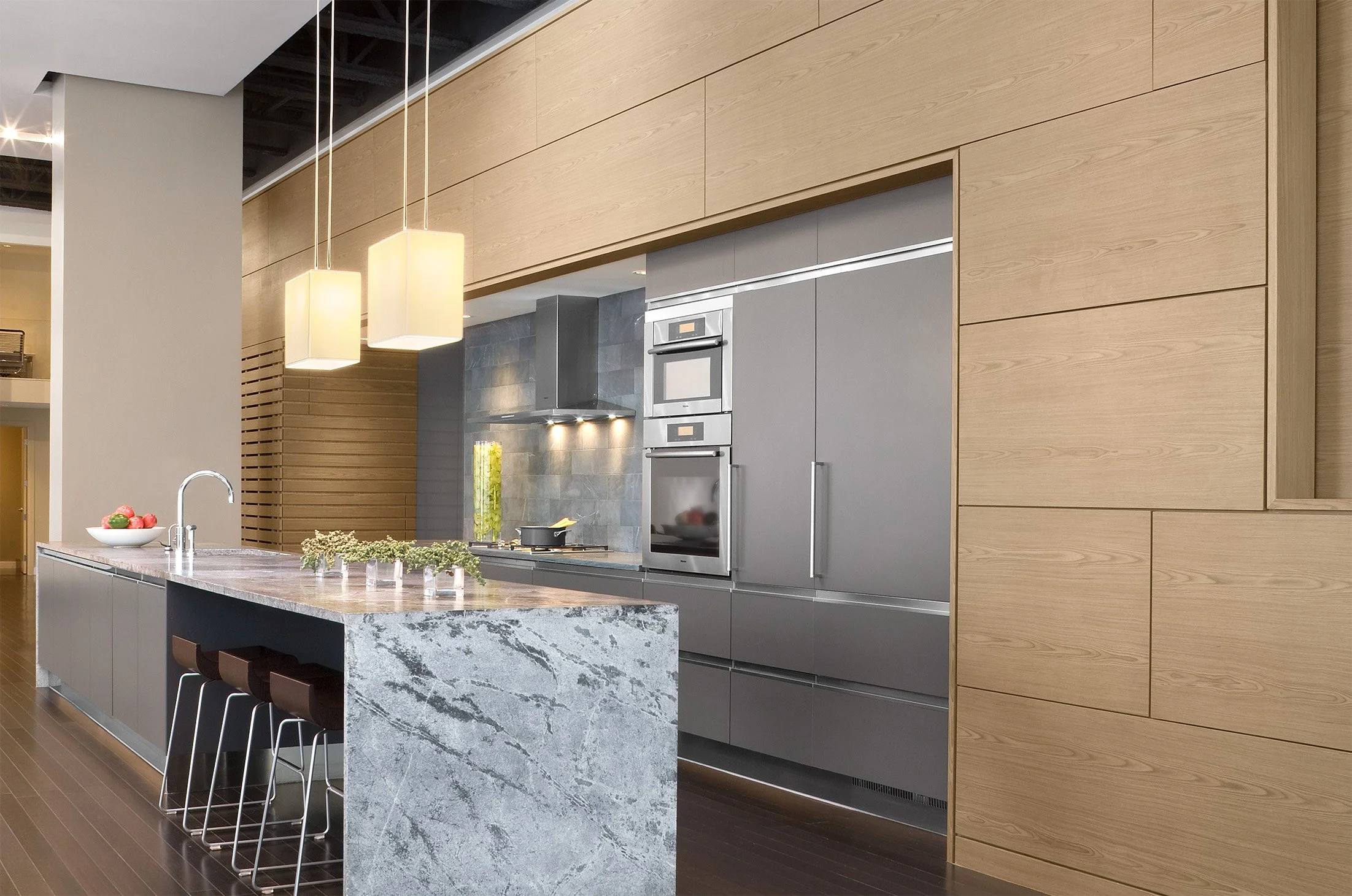 Modern gray kitchen cabinets recessed into a wall with contemporary wood paneling in a large loft space