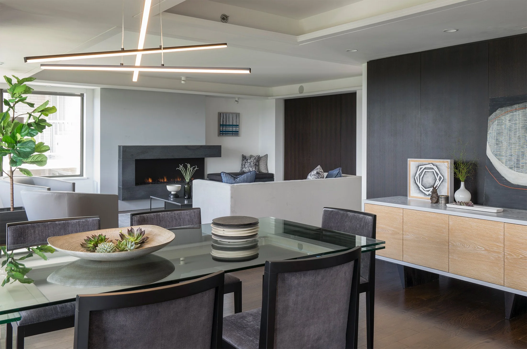 A renovated condominium interior with custom gas fireplace, modern tray ceilings and dark wood wall paneling