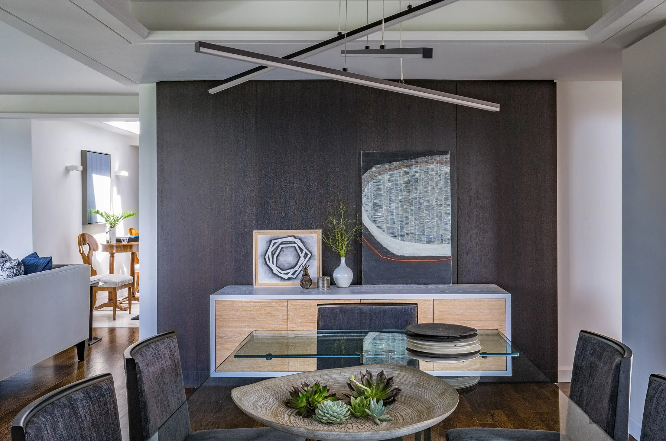 Dining room interior design featuring modern tray ceilings, a linear pendant over the table, and contemporary wood wall paneling