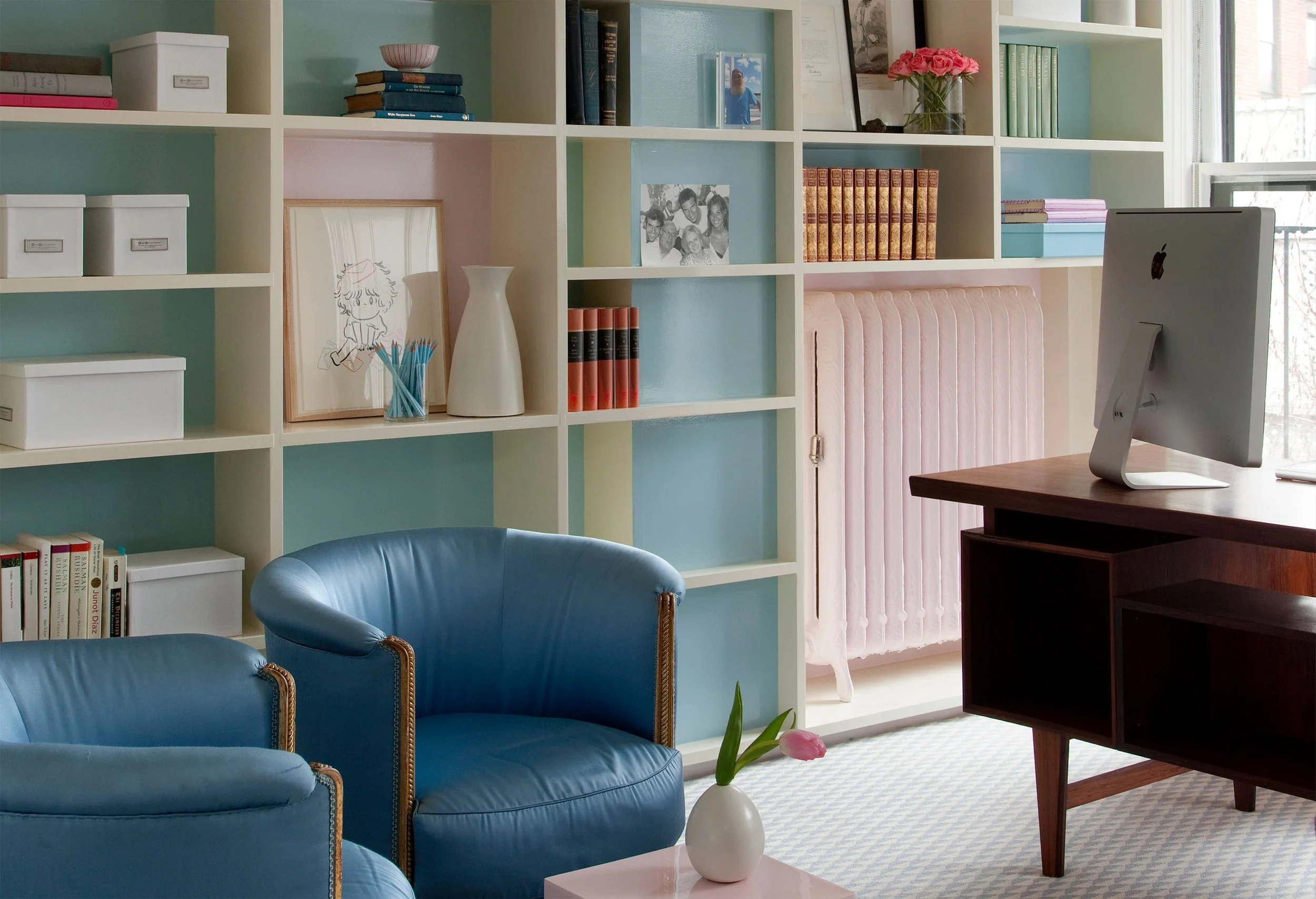 A home office featuring a custom bookcase with contrasting blue and pink backs
