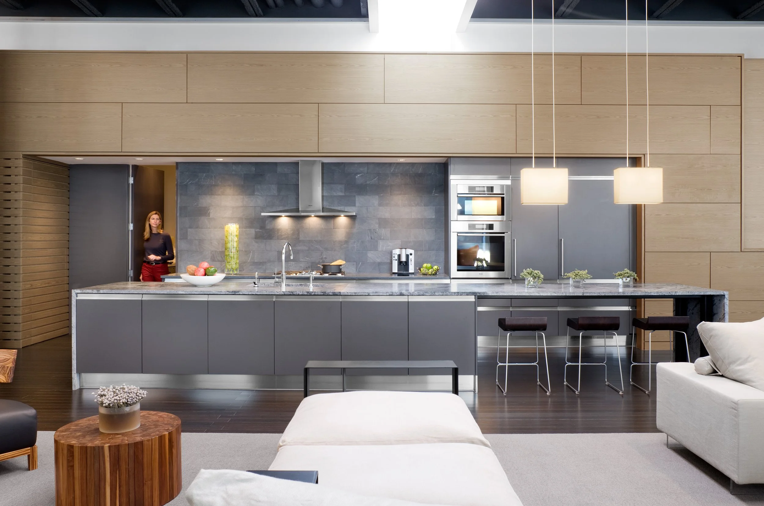 A modern kitchen in a loft condominium featuring a skylight and large stone island with an integrated dining table