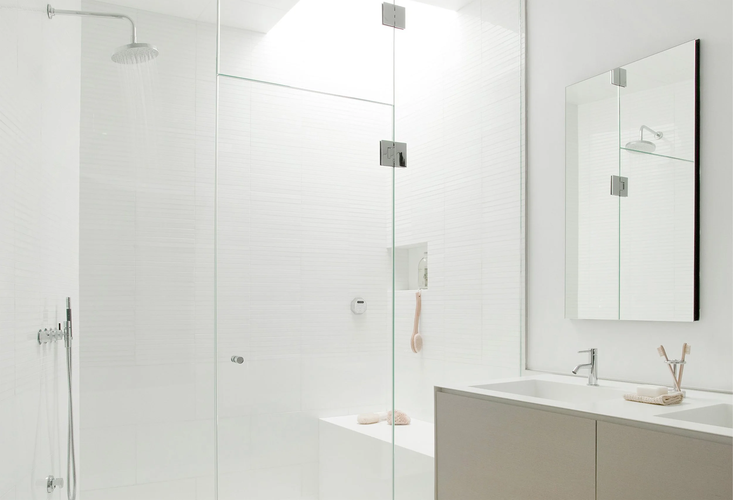 A bright all white bathroom featuring frameless glass steam shower containing a skylight