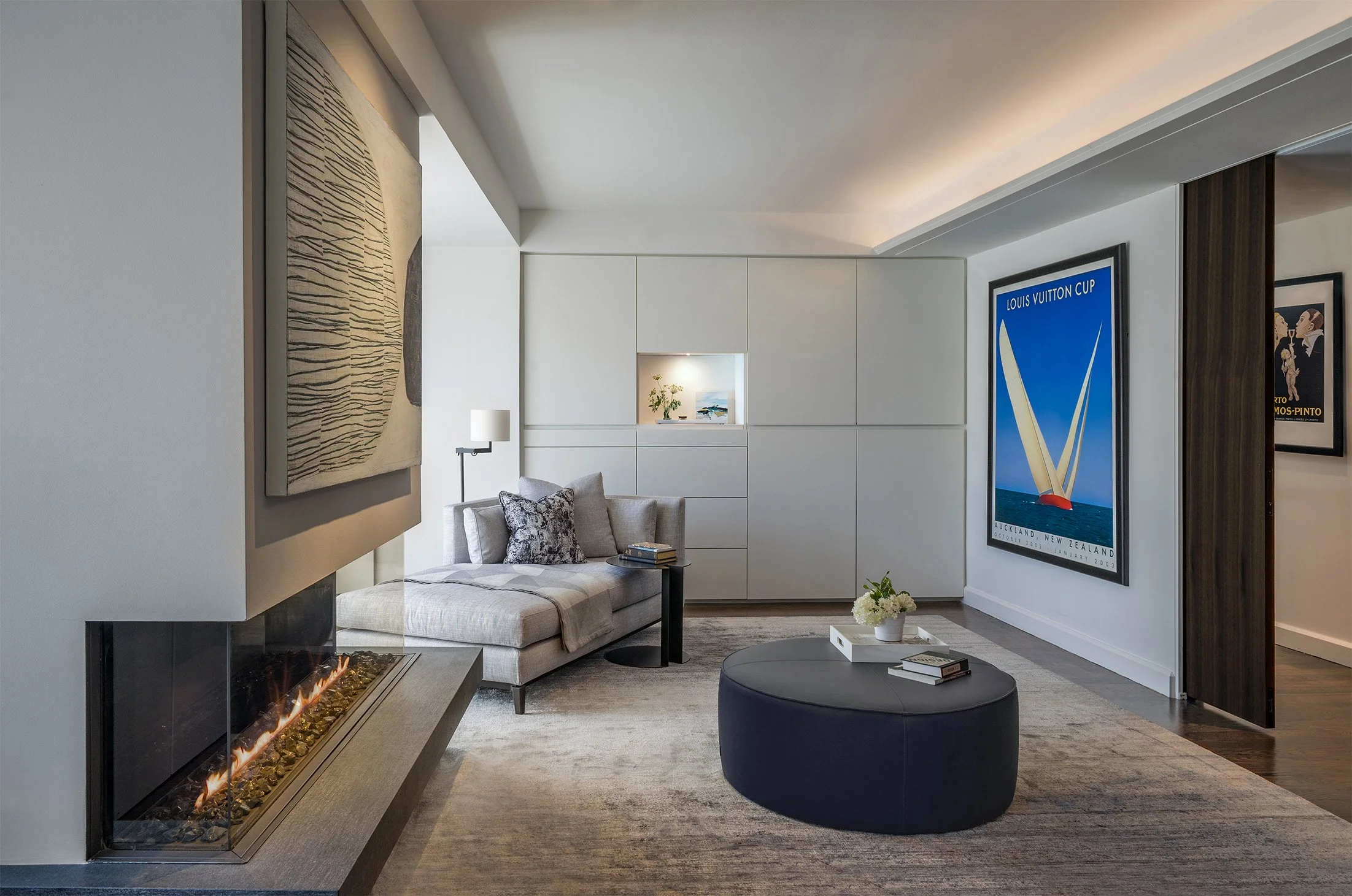 A modern primary bedroom featuring a three-sided fireplace and custom built in storage