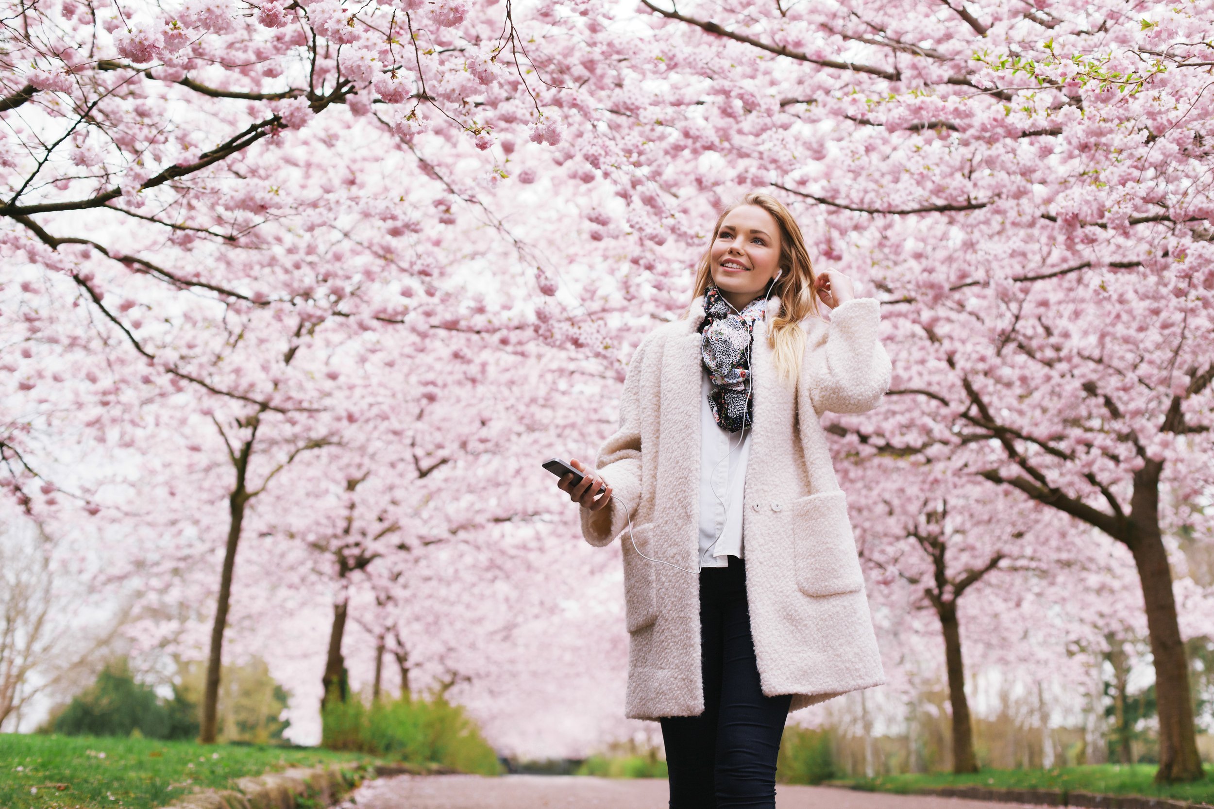 smiling-young-woman-with-mobile-phone-listening-to-music-in-park-attractive-young-fema-SBI-301327465.jpg